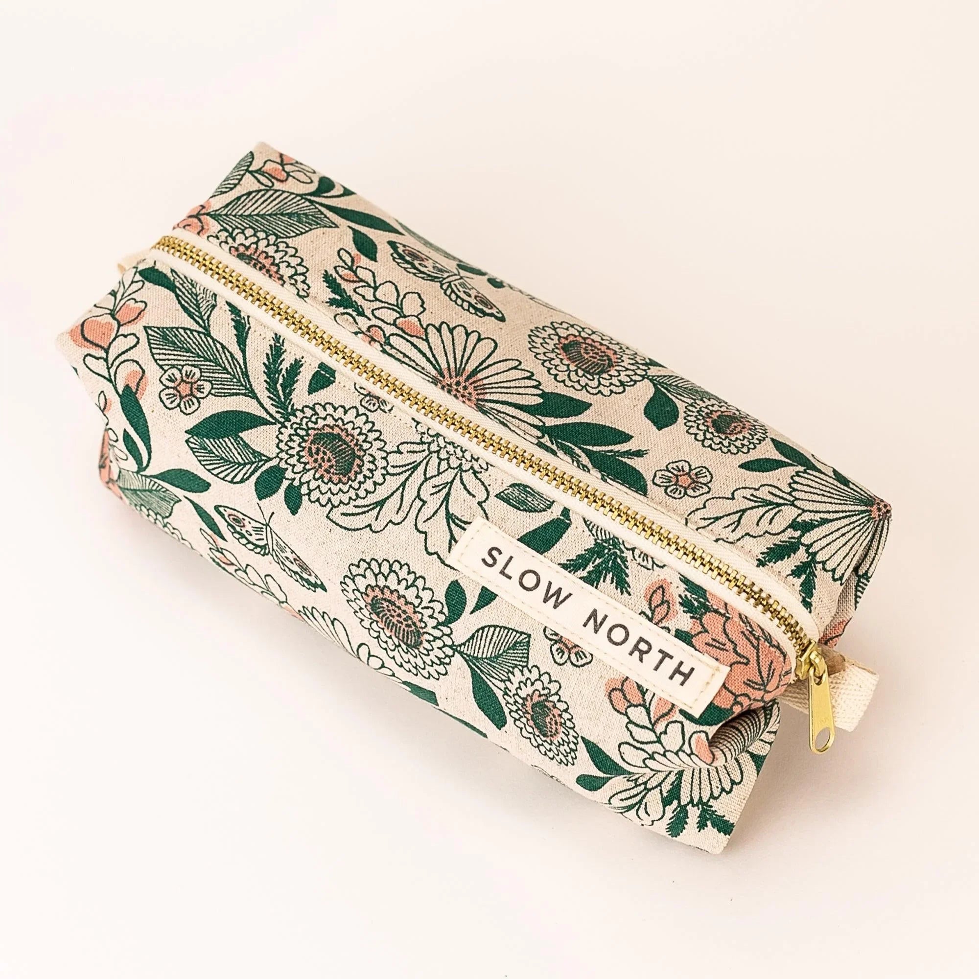 Floral fabric travel pouch with gold zipper and Slow North label on white background