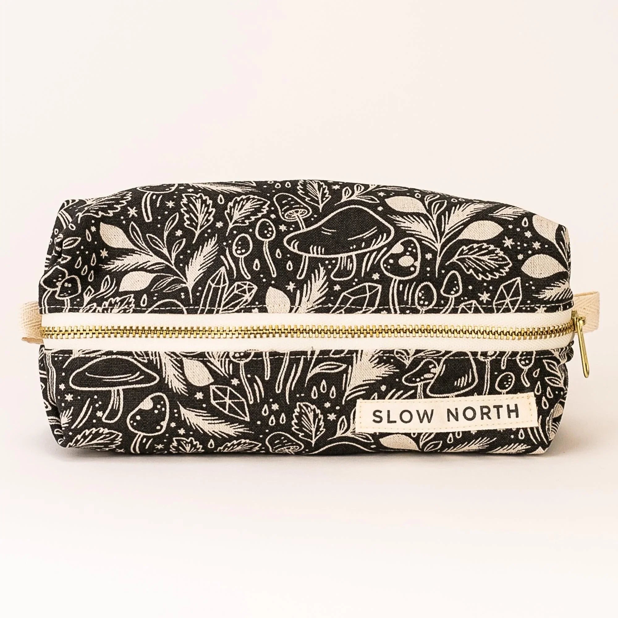 Black and white travel pouch with mystical mushroom and leaf pattern, gold zipper, Slow North label