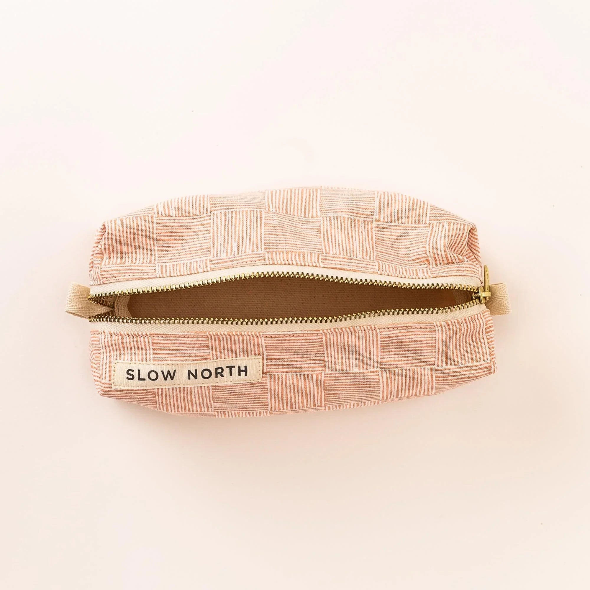 Pink pampas patterned travel pouch with zipper and Slow North logo on white background