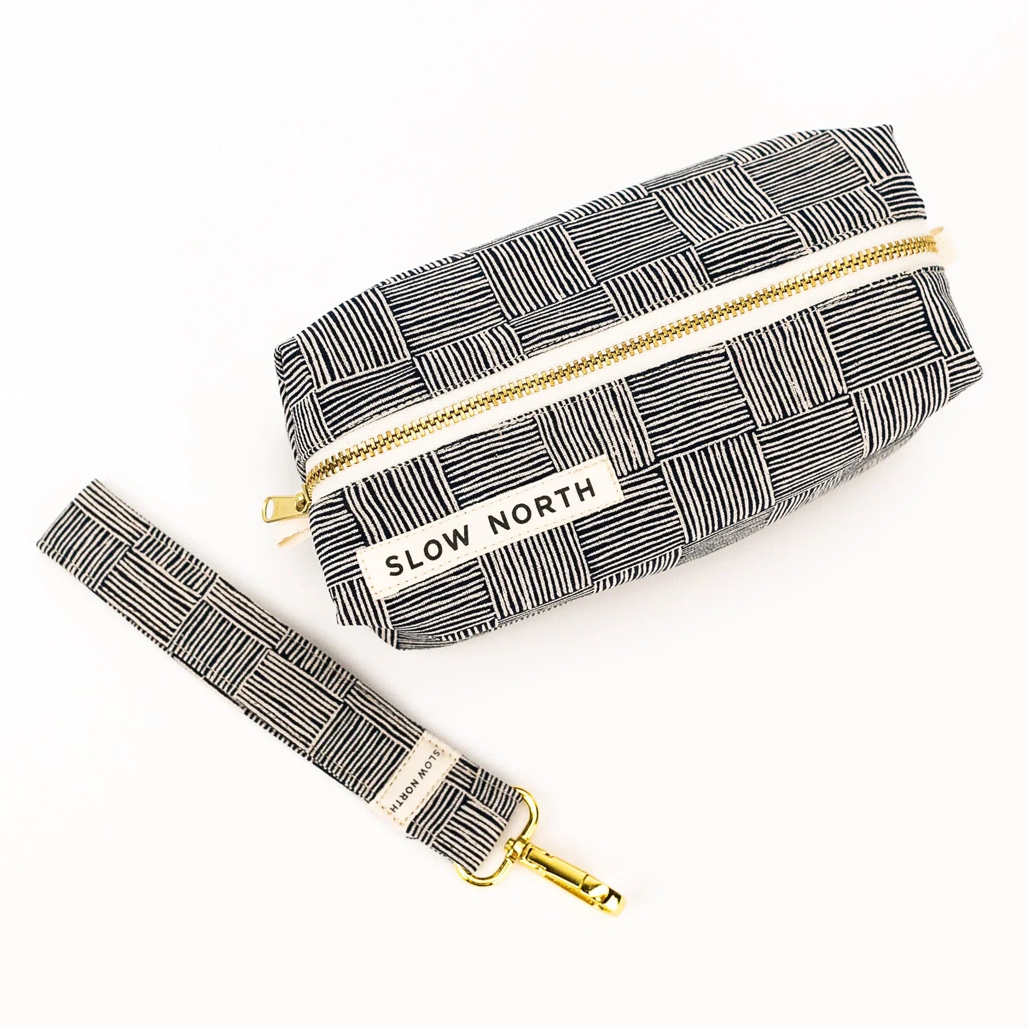 Slow North travel pouch and matching wristlet with black and white striped geometric pattern and gold zipper
