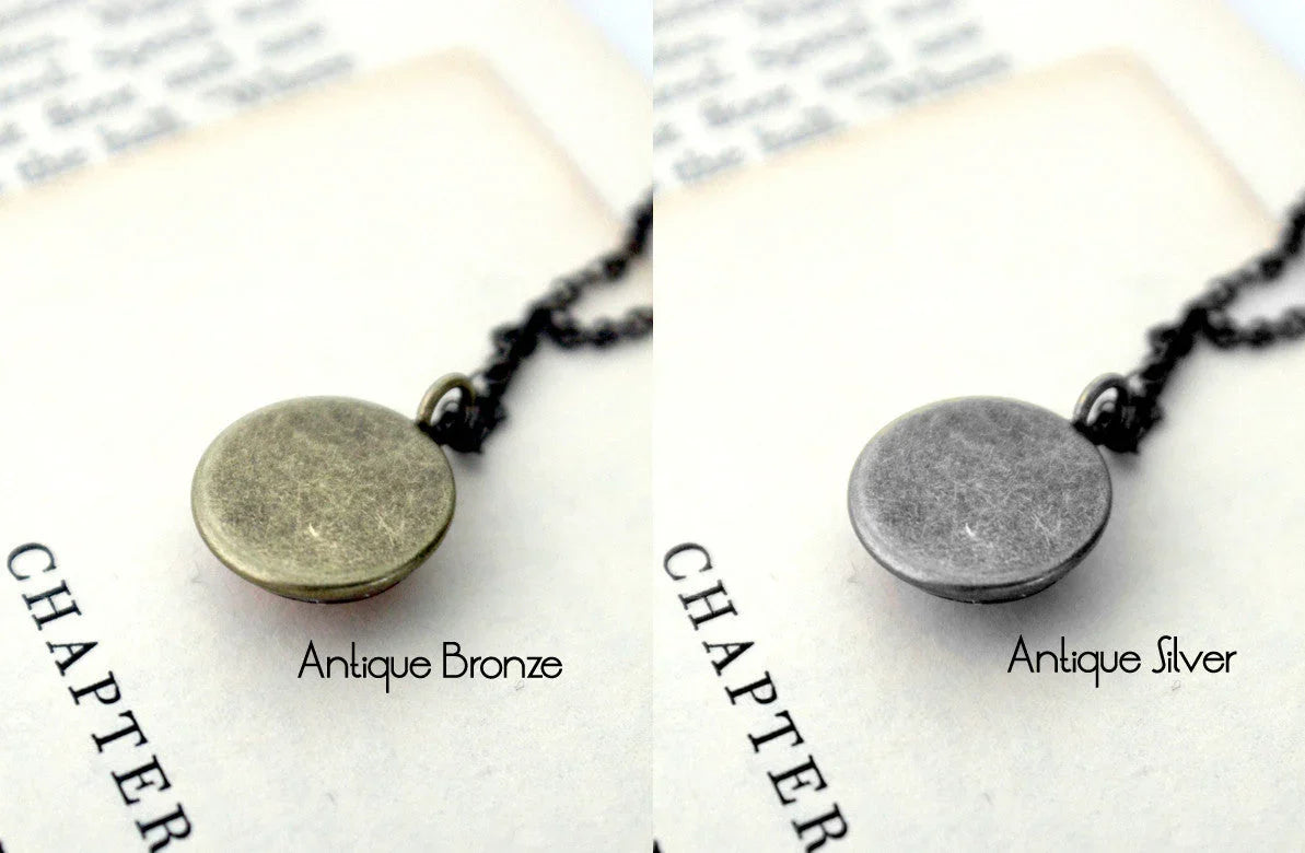 Antique bronze and silver round locket necklaces on book page, Qu!rk Boutique jewelry