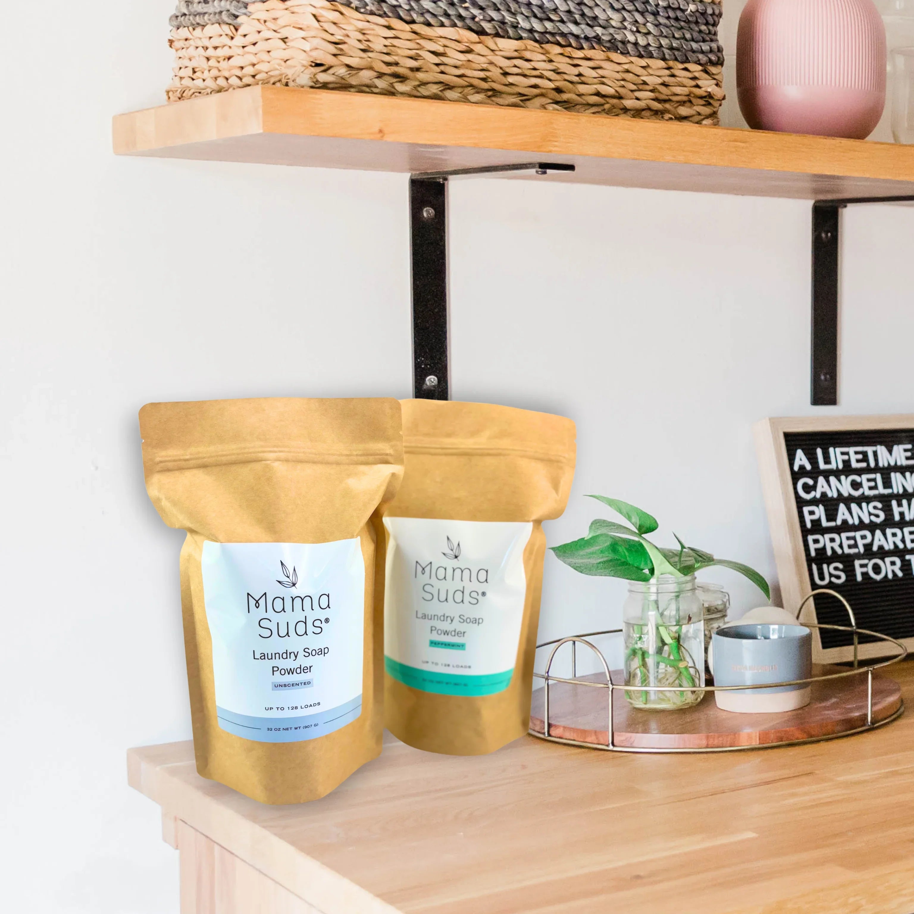 Mama Suds laundry soap powder pouches on wood shelf with plant and mug at Qu!rk Boutique