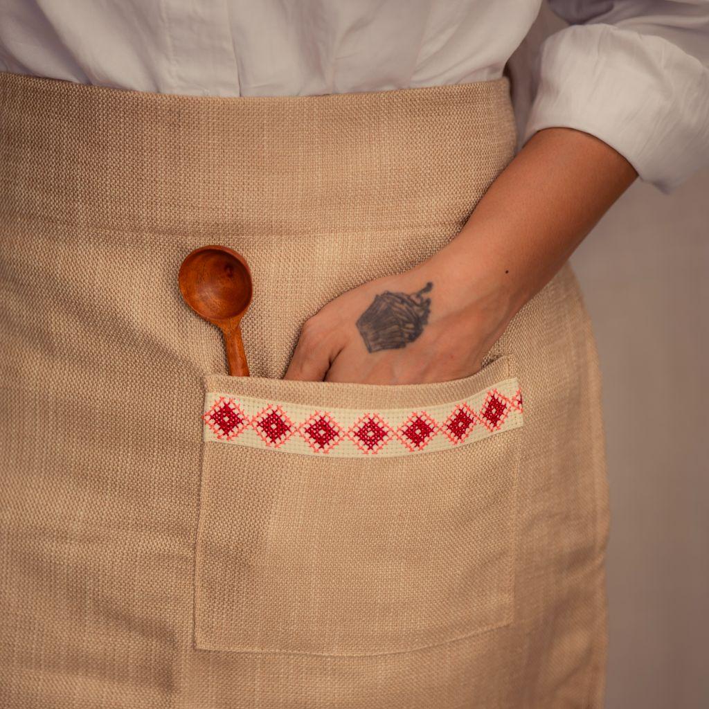 Handmade beige apron with red embroidered pocket, wooden spoon, and tattooed hand, Qu!rk Boutique