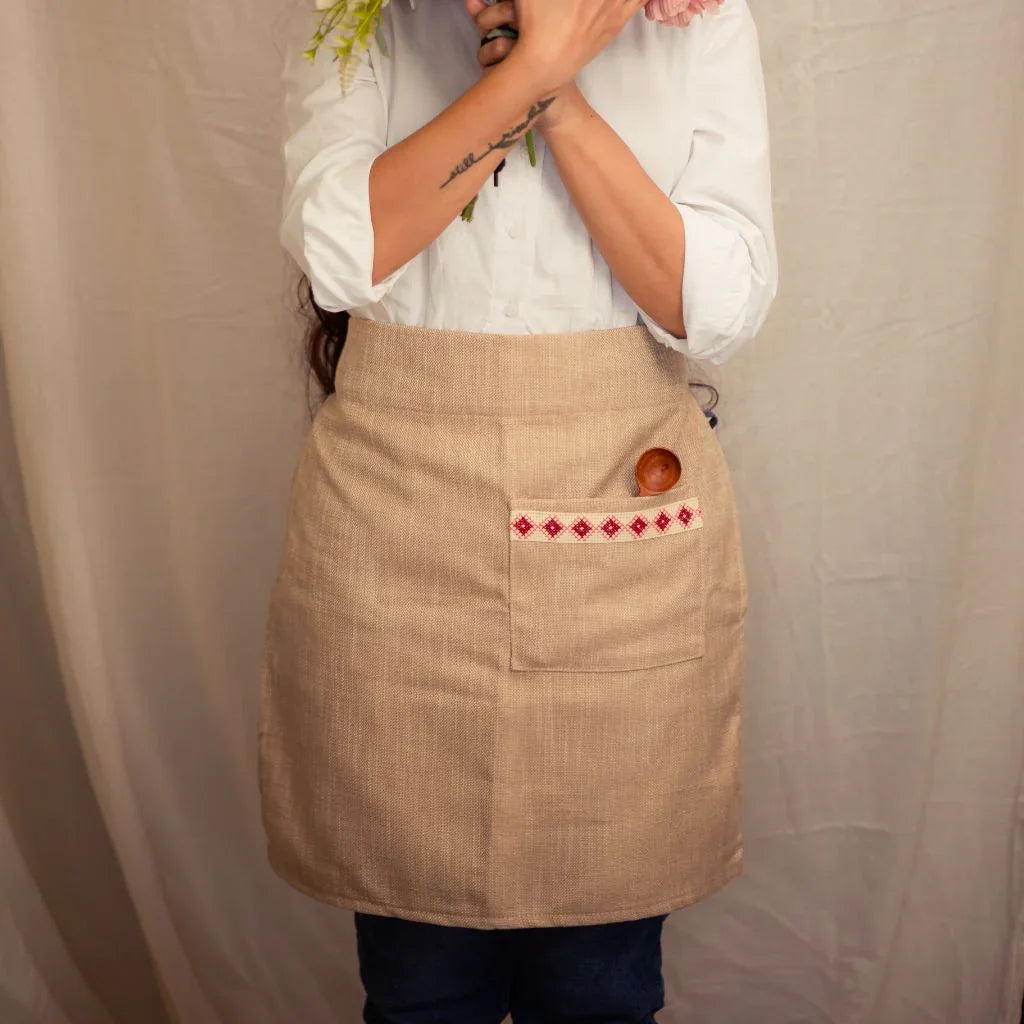 Woman wearing a natural linen half apron with embroidered pocket, holding flowers, eco-friendly gift