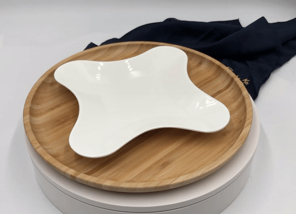 White ceramic star-shaped dish on round bamboo serving tray with dark cloth