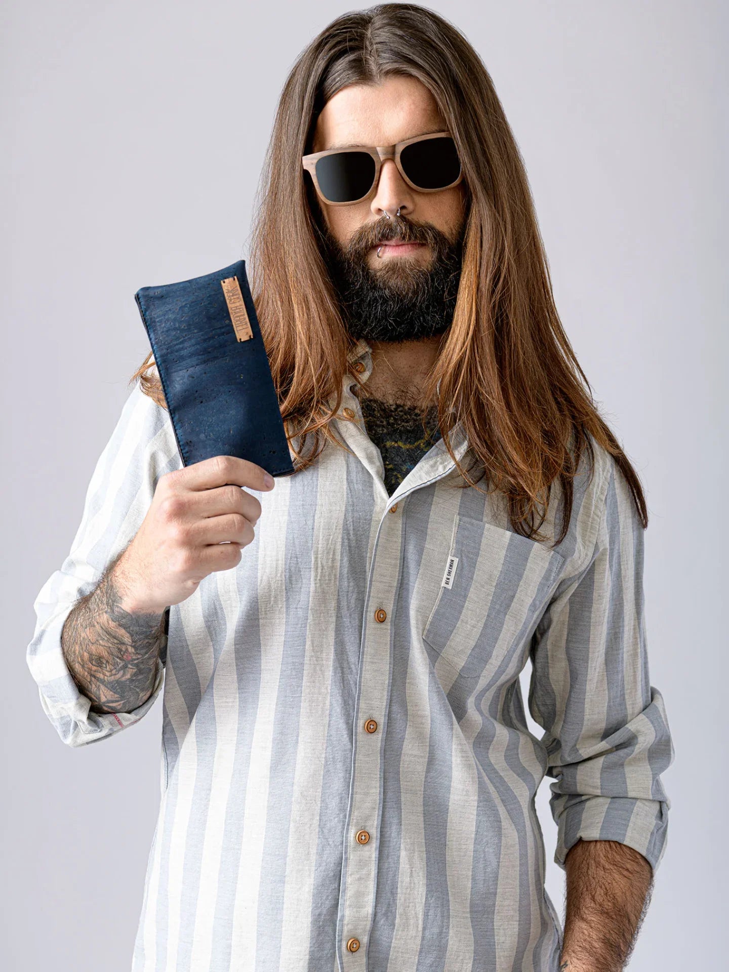 Bearded man in striped shirt and sunglasses holds a navy cork wallet, Qu!rk Boutique product