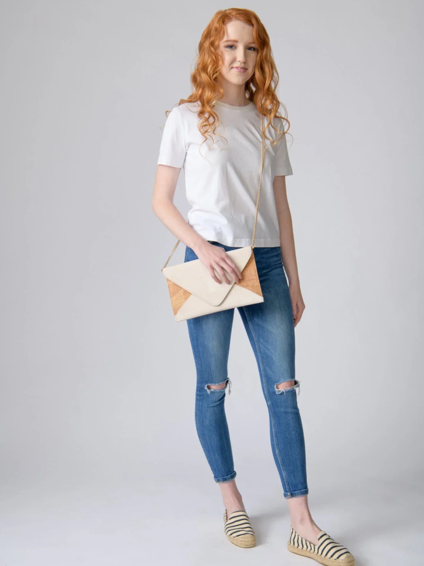 Woman in white t-shirt, jeans, striped espadrilles, and envelope crossbody bag at Qu!rk Boutique