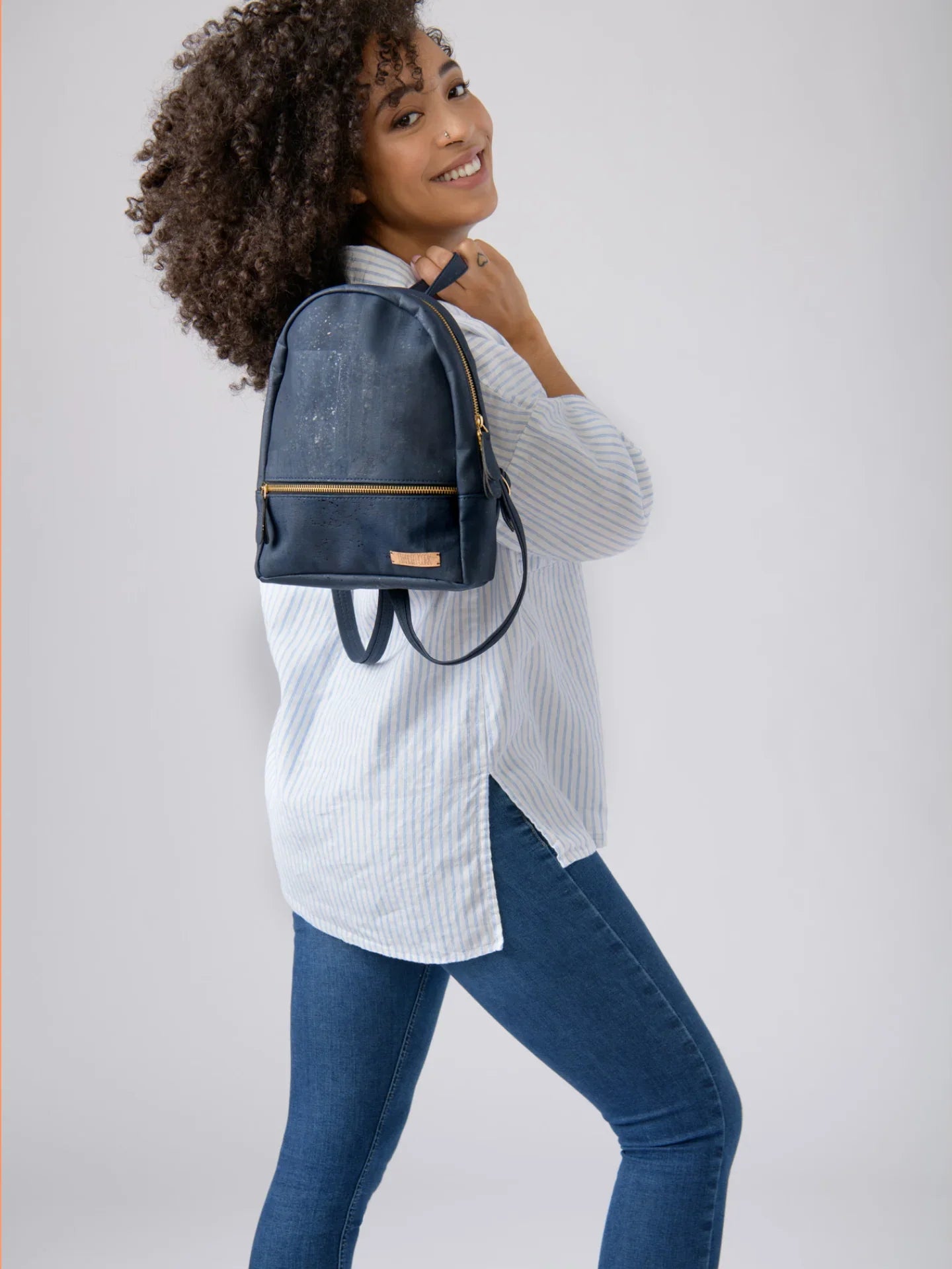 Woman wearing a blue mini backpack from Qu!rk Boutique, styled with jeans and striped shirt