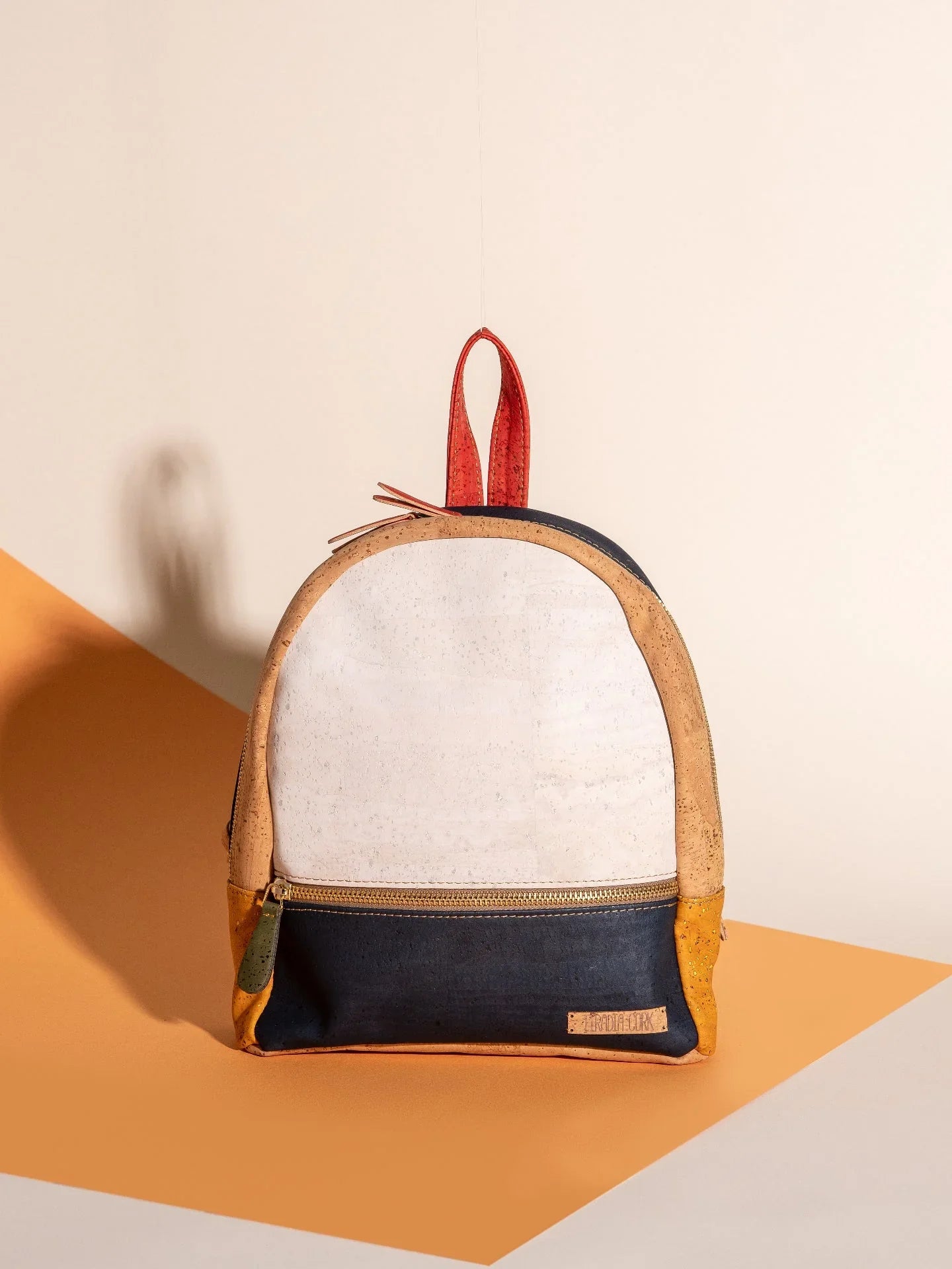 Eco-friendly colorblock backpack with cork trim, displayed on a geometric background at Qu!rk Boutique.