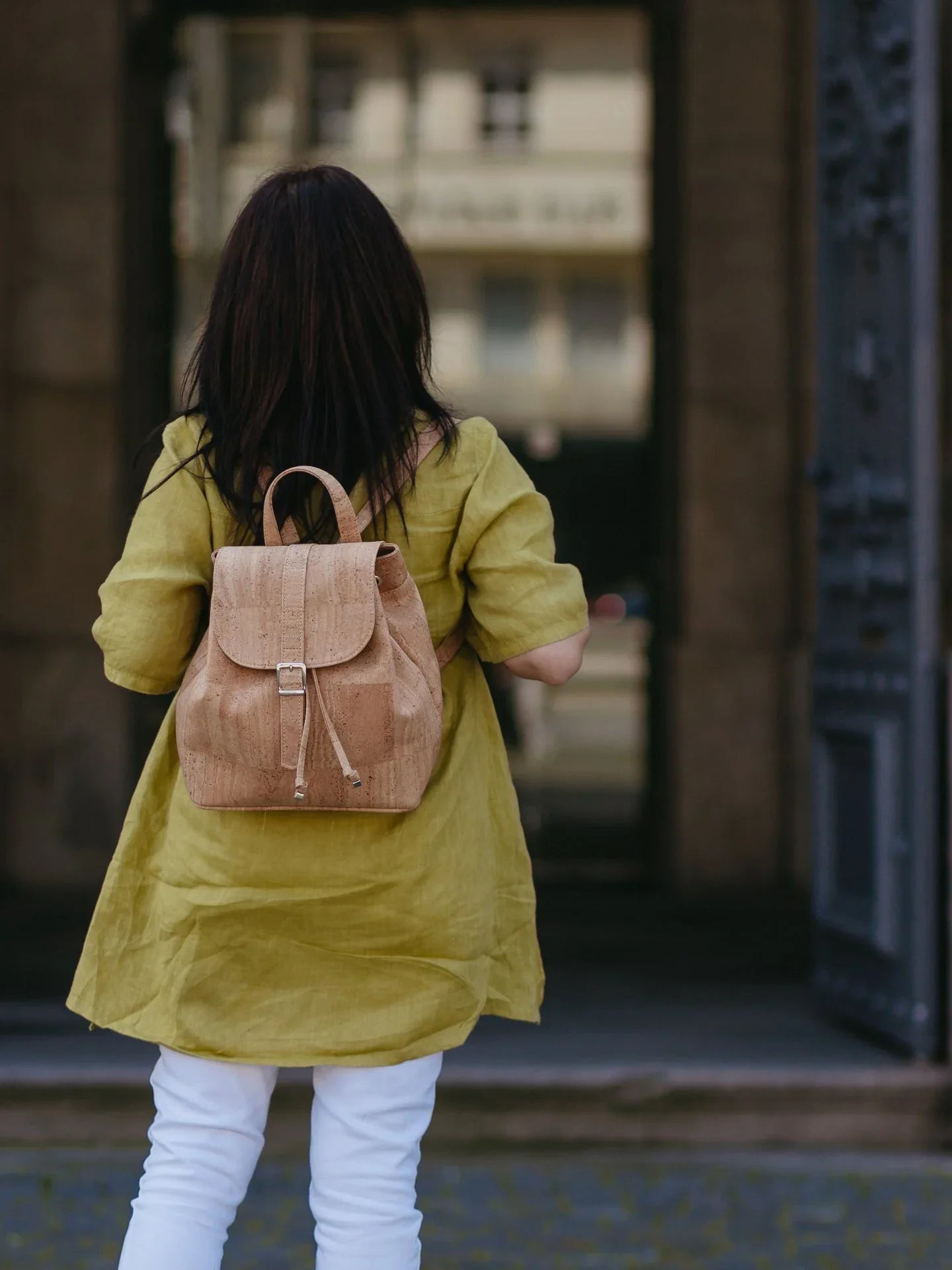 Woman in green tunic and white pants with eco-friendly tan backpack, Qu!rk Boutique style