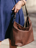 Woman holding a brown cork handbag, styled with a blue dress, eco-friendly fashion accessory