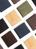Assorted sustainable cork wallets in brown, black, green, blue, and natural shades on white background.