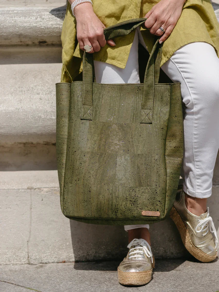 Woman holding green recycled tote bag, wearing gold shoes and white pants, Qu!rk Boutique