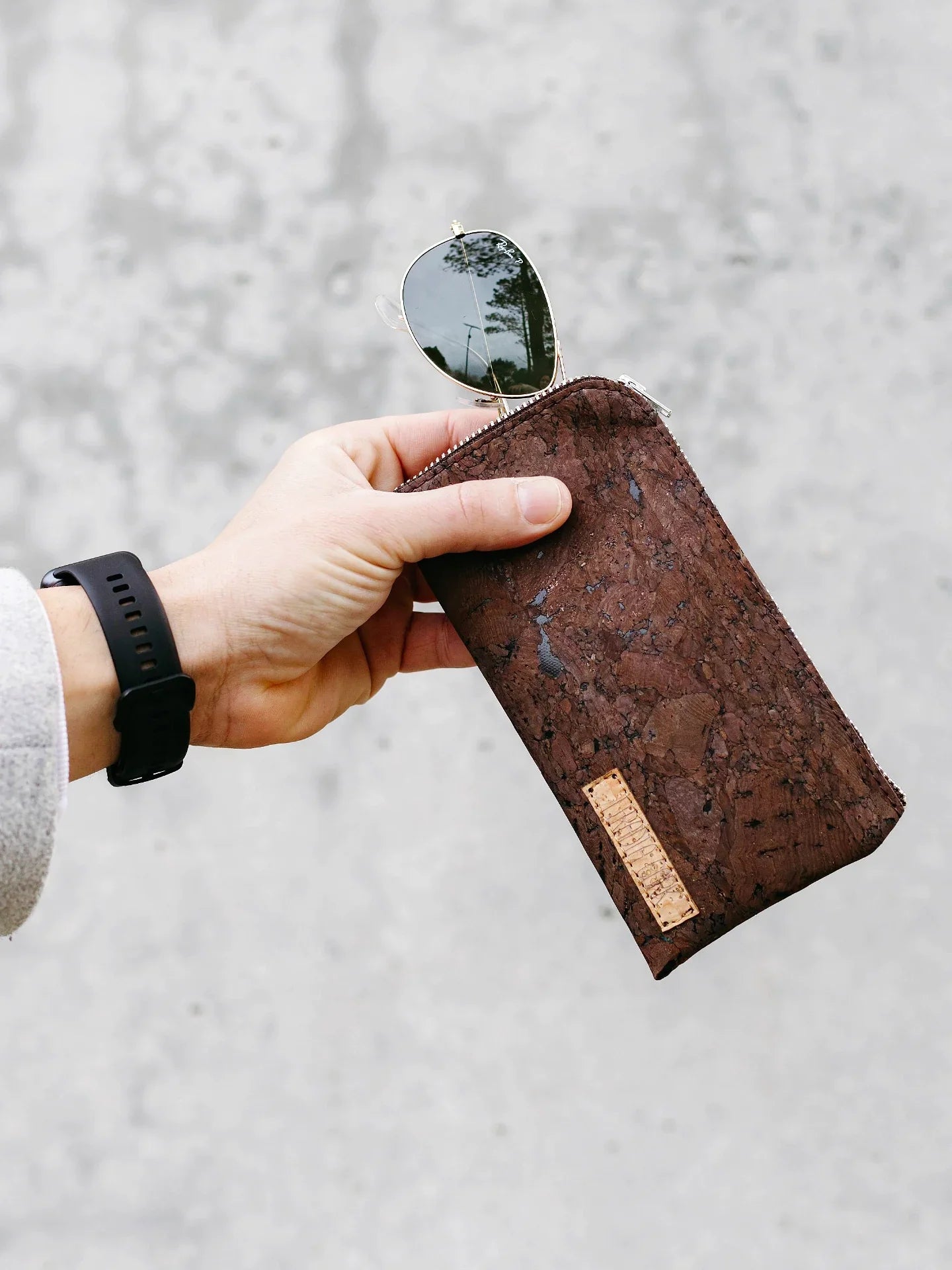 Hand holding eco-friendly brown cork sunglasses case with aviator sunglasses, Qu!rk Boutique