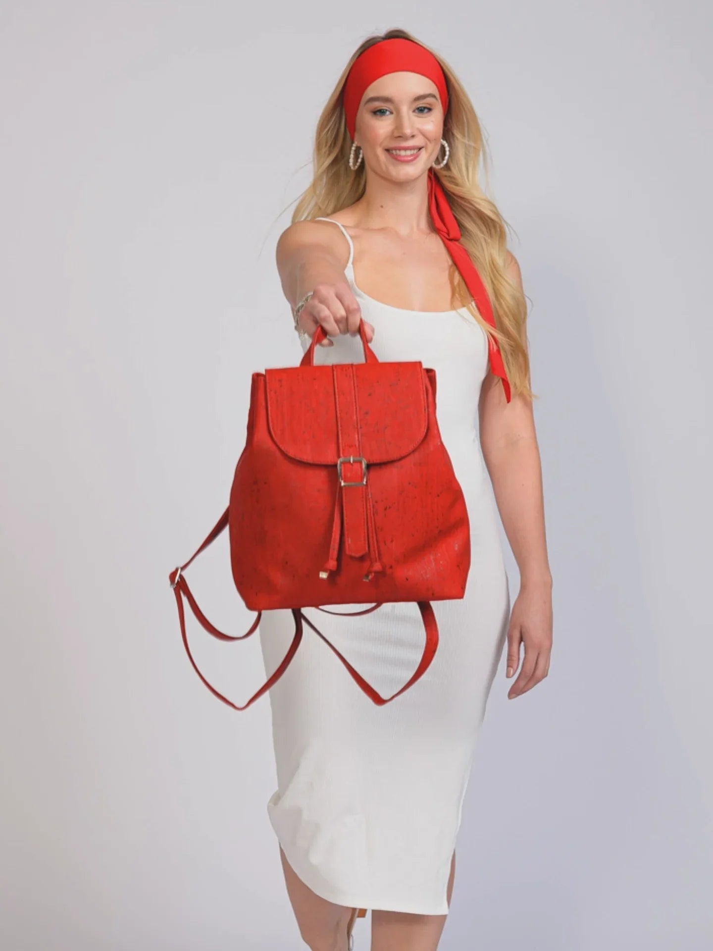 Woman in white dress and red headband holding bold red backpack, Qu!rk Boutique fashion