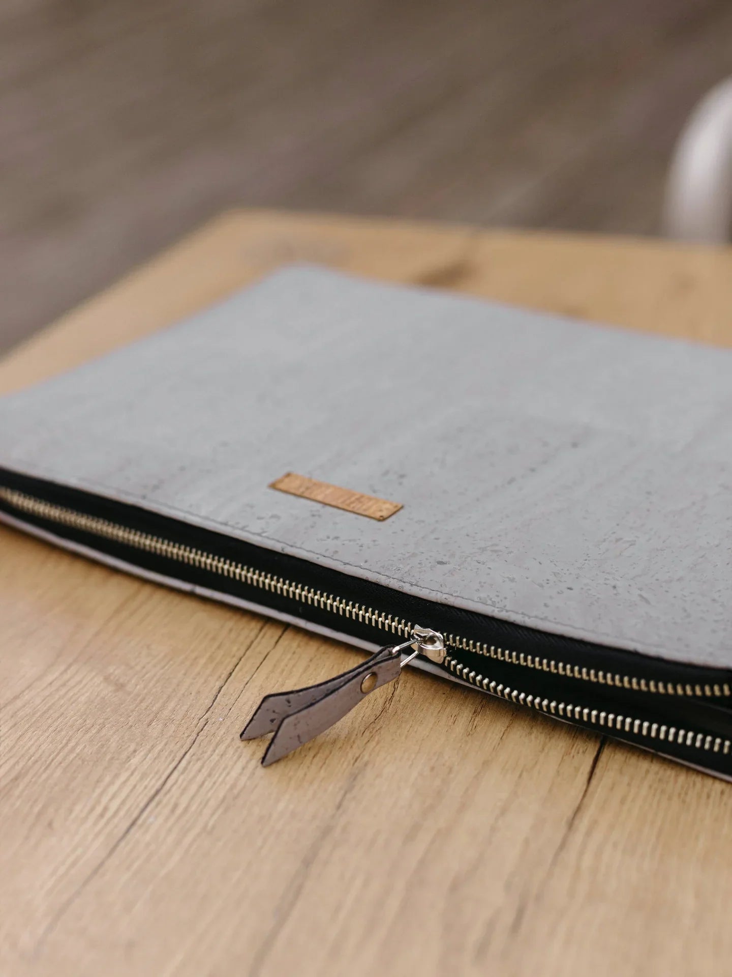 Minimalist grey cork zip pouch with leather puller on wooden table, eco-friendly accessory