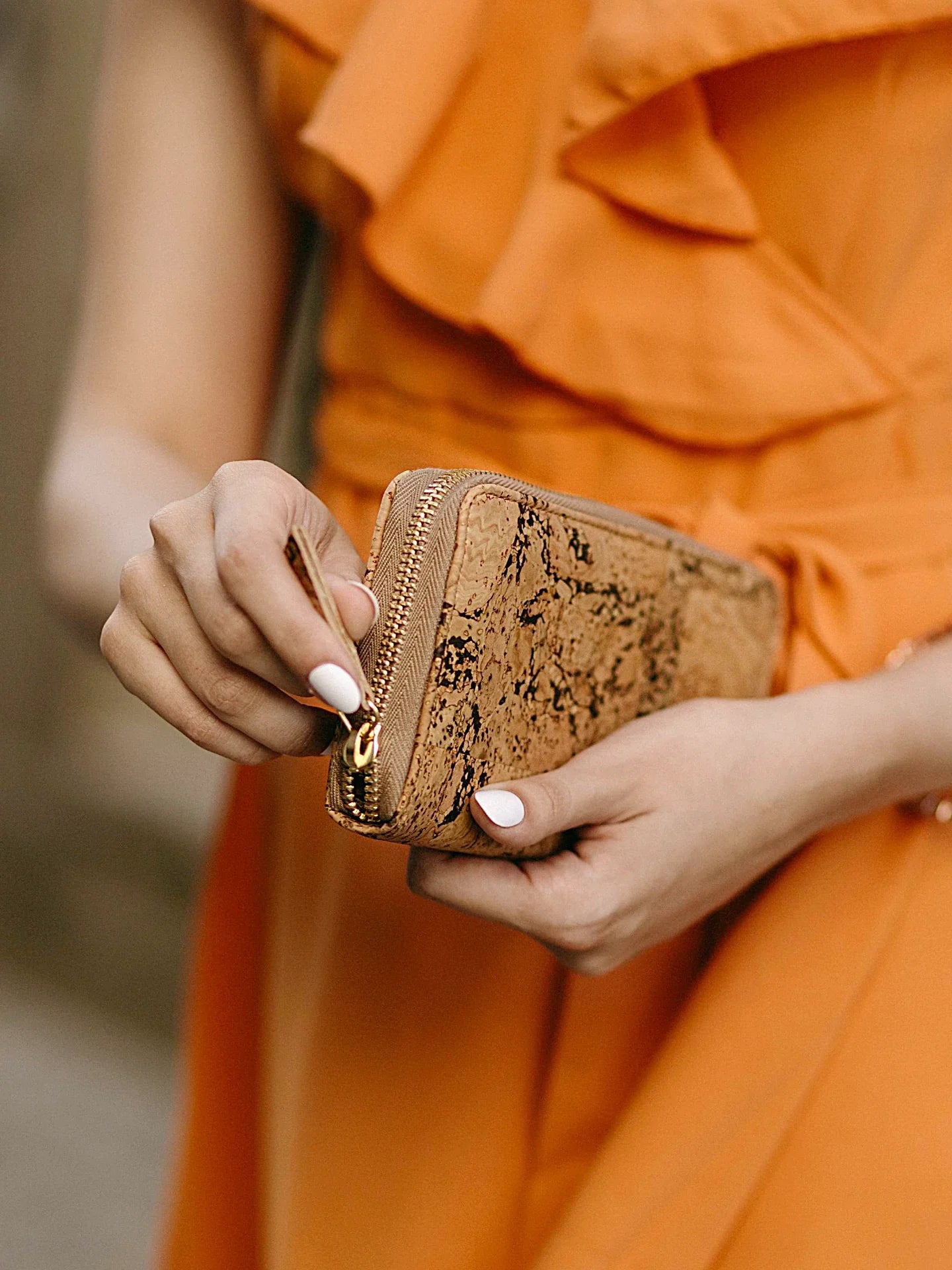 Woman in orange dress holding a sustainable cork clutch purse, Qu!rk Boutique style