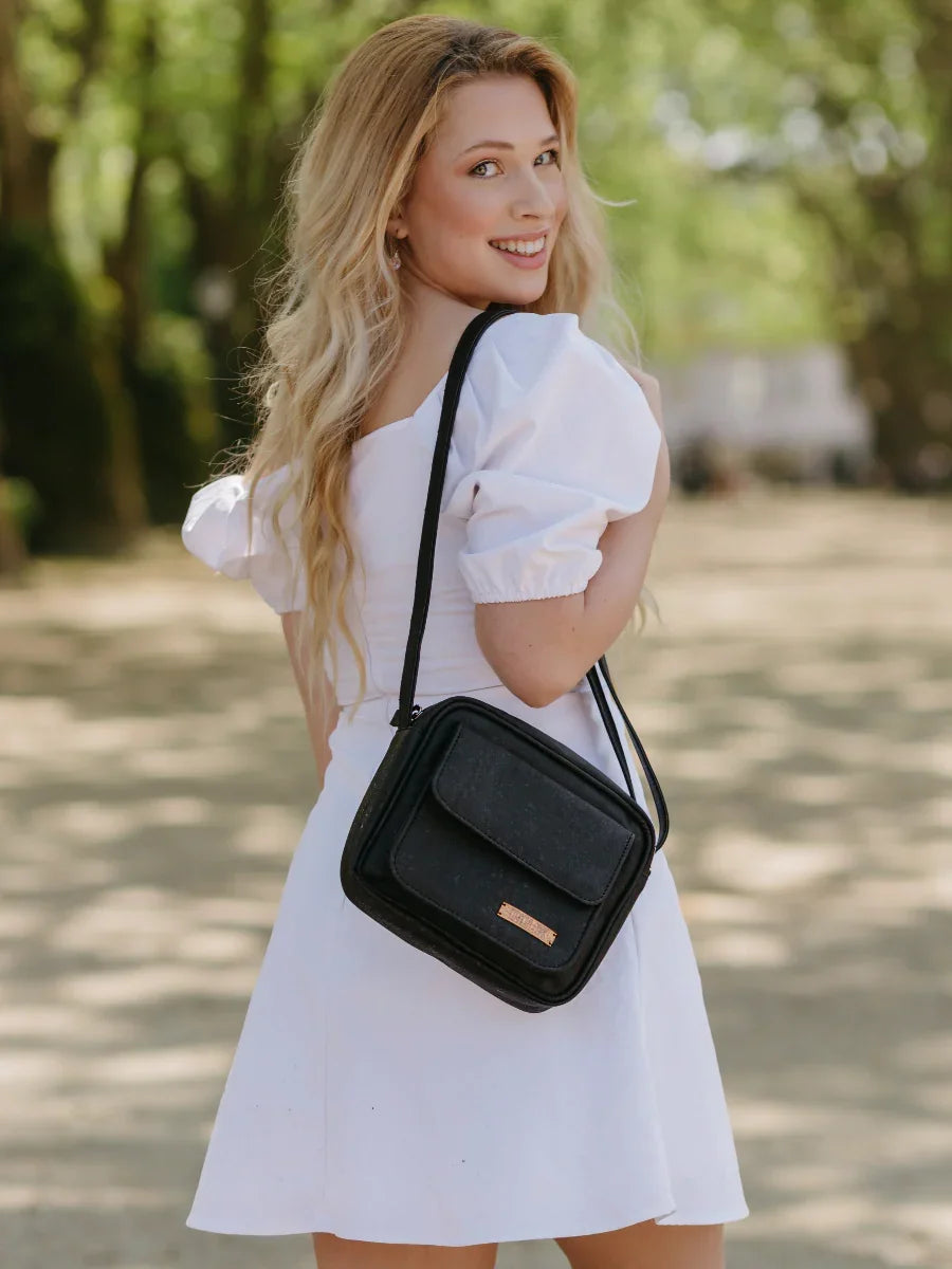 Woman in a white dress outdoors with a black crossbody bag from Qu!rk Boutique