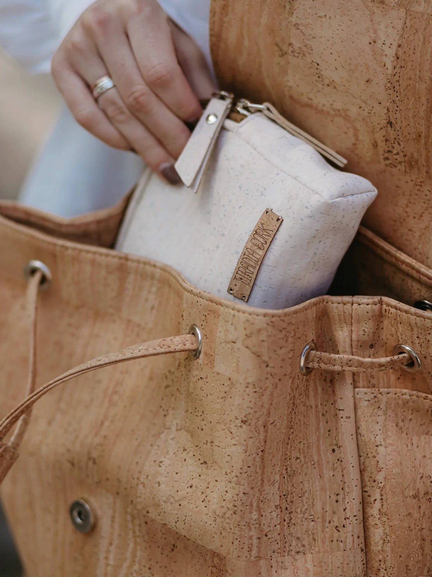 Hand placing eco-friendly cork pouch into sustainable cork tote bag at Qu!rk Boutique