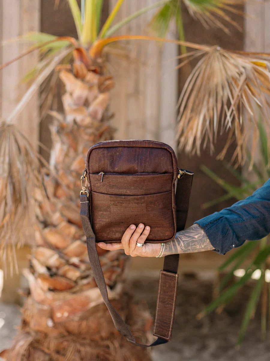Ethically sourced brown crossbody bag held in front of a palm tree at Qu!rk Boutique
