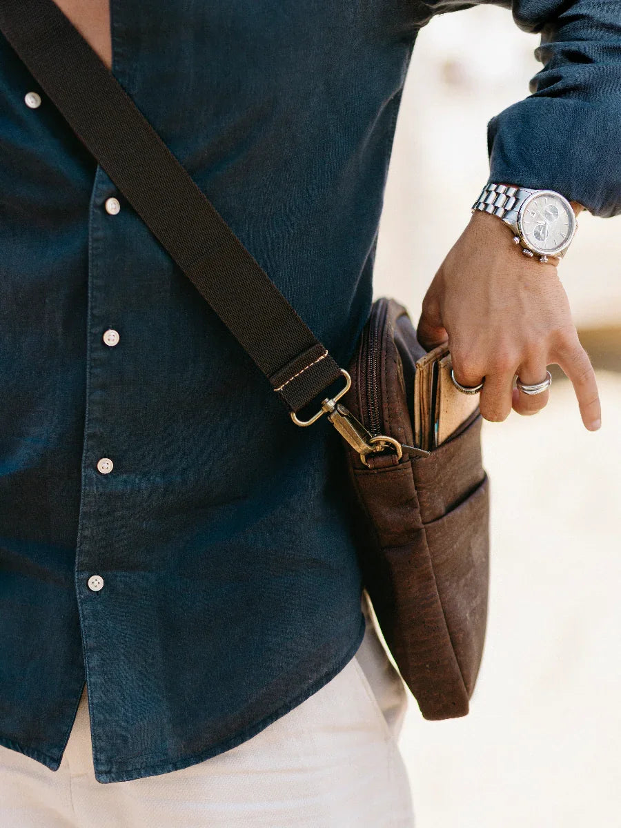 Man in navy shirt and watch carrying eco-friendly brown crossbody bag with wallet