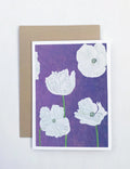 Notecard with white poppy flowers on a violet background and a brown envelope