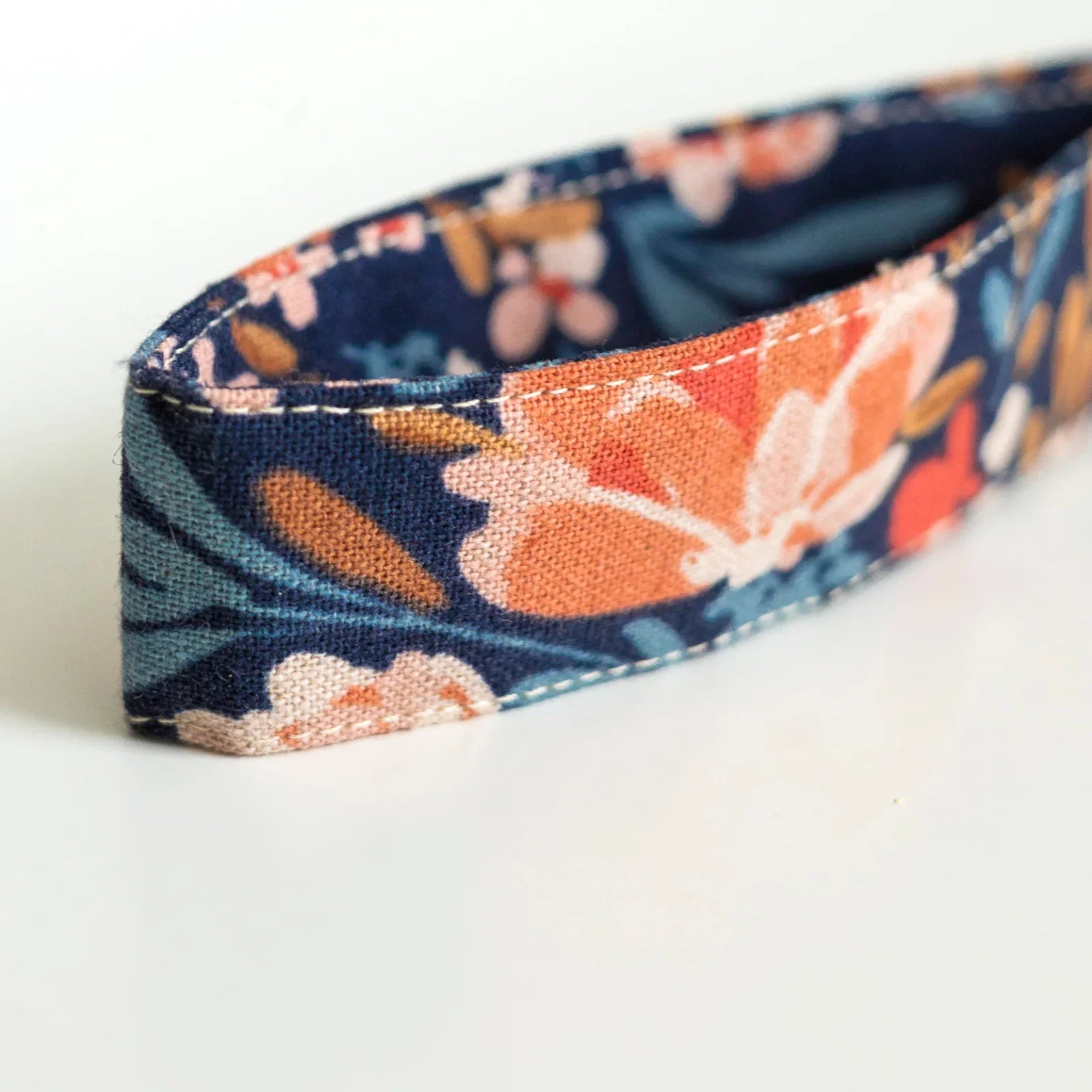 Close-up of a fabric wristlet with vibrant floral pattern on dark background, Qu!rk Boutique