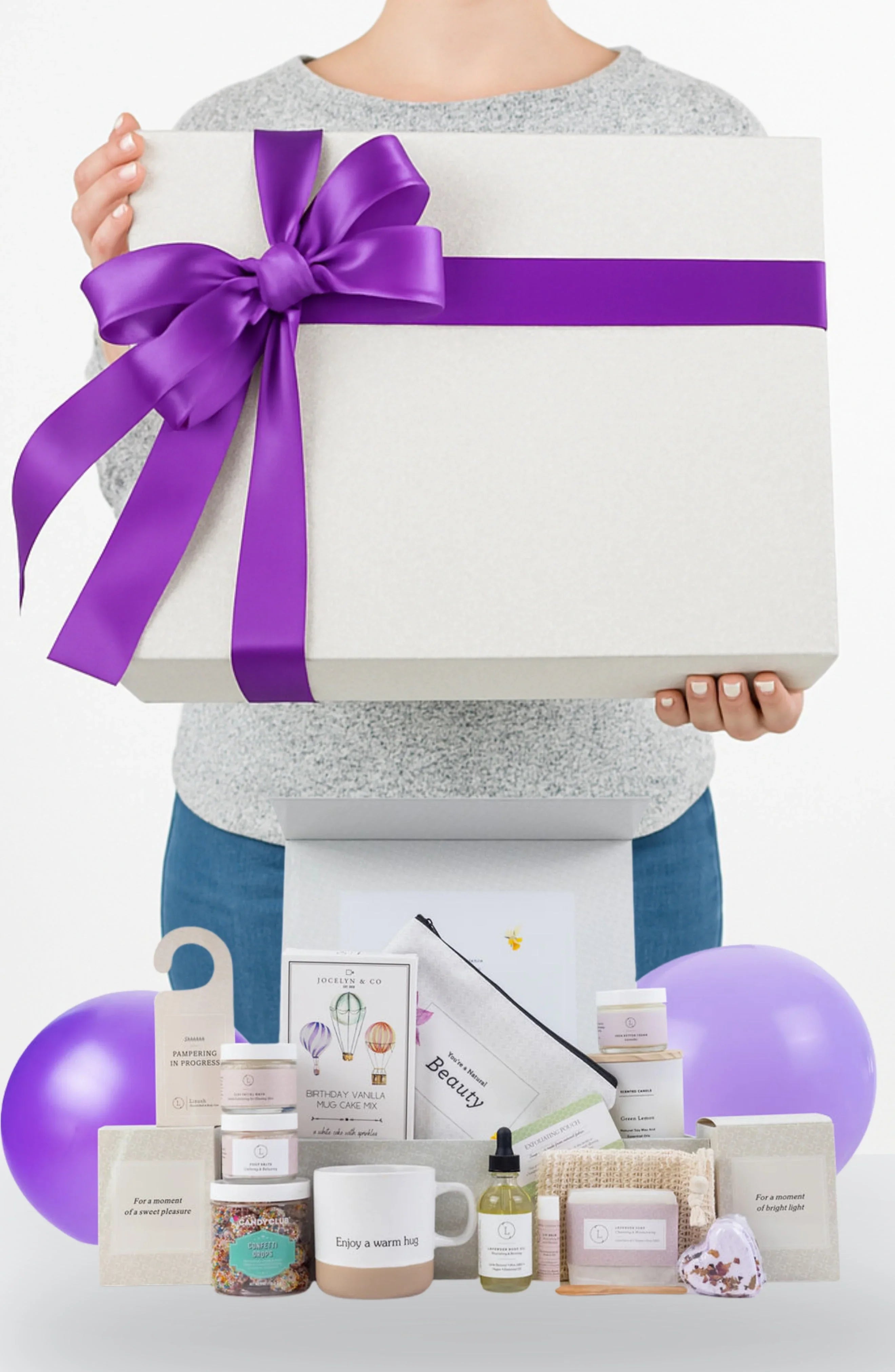 Woman holding large gift box with purple ribbon, pampering birthday gift set, Qu!rk Boutique