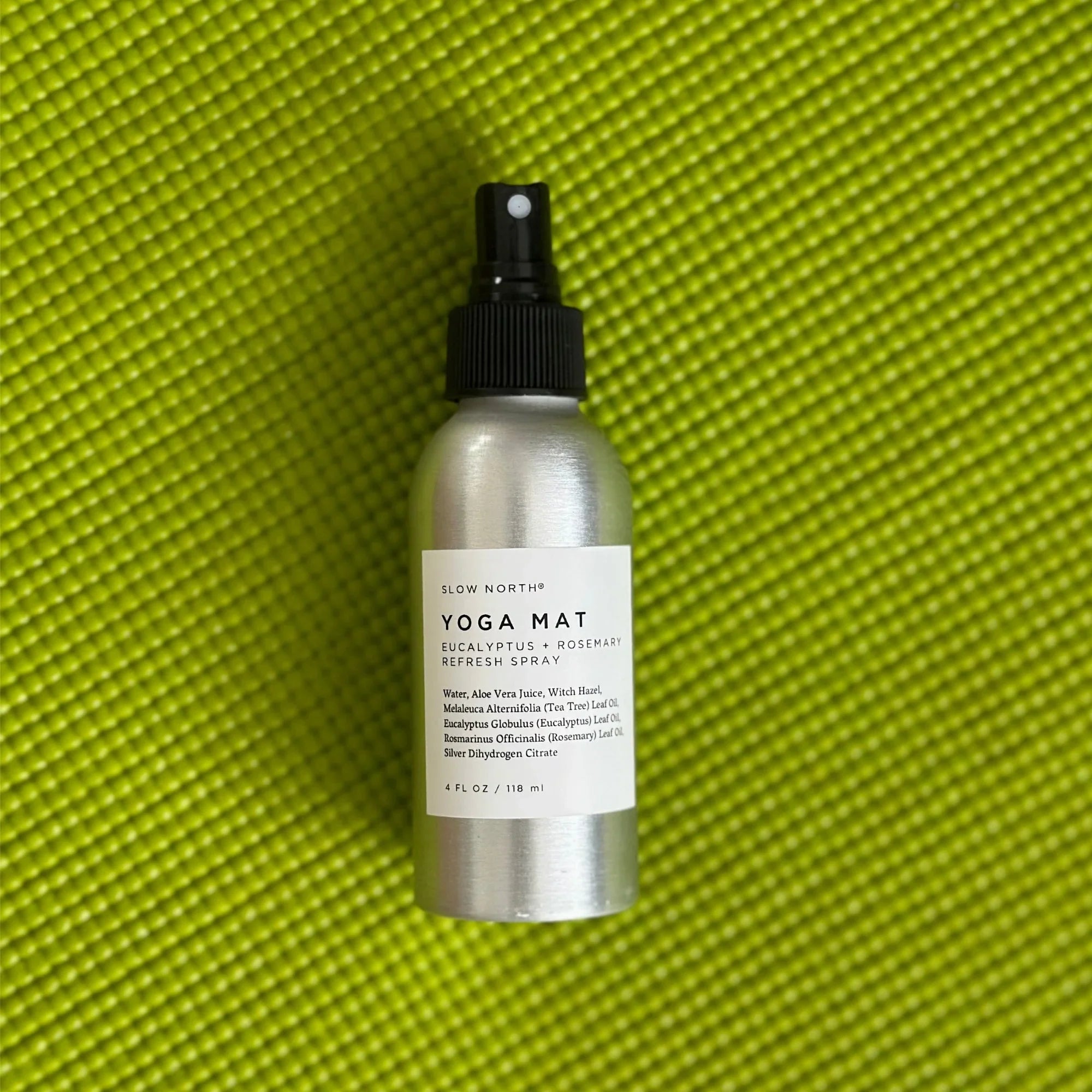 Silver spray bottle of Slow North eucalyptus rosemary yoga mat refresh spray on green textured yoga mat