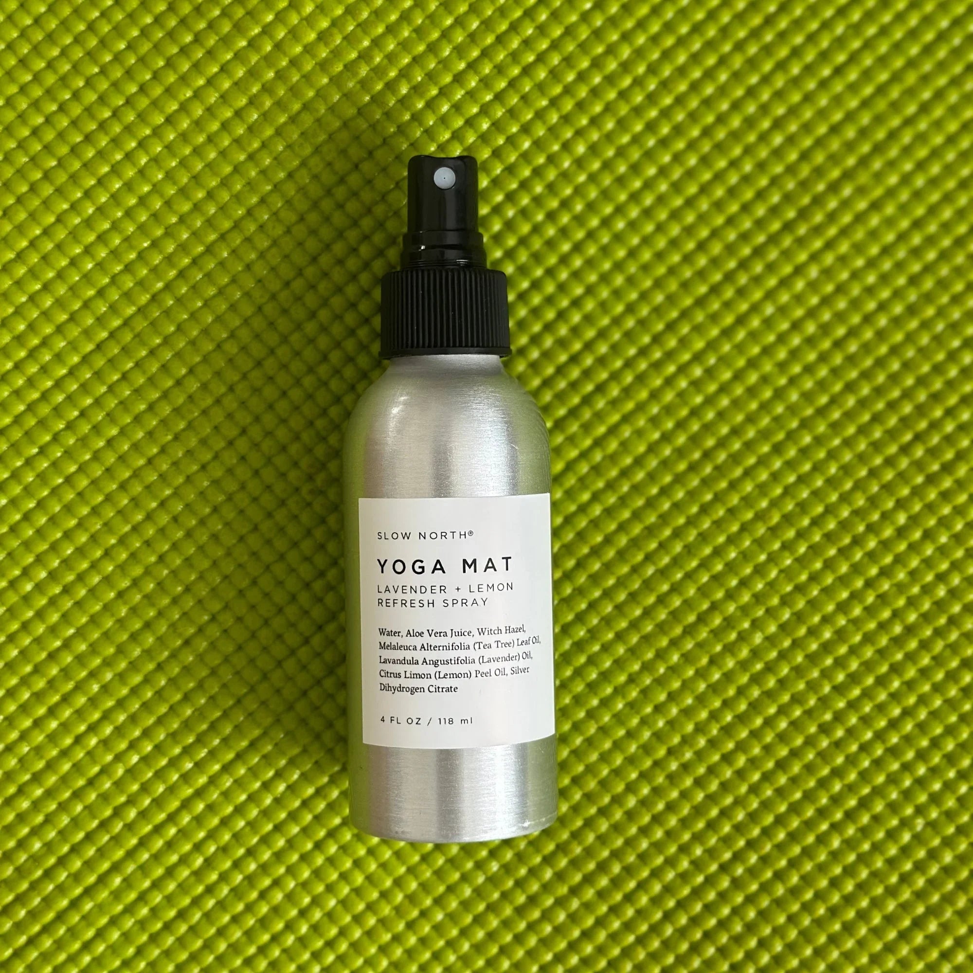 Silver bottle of Slow North Yoga Mat Lavender and Lemon Refresh Spray on green textured yoga mat