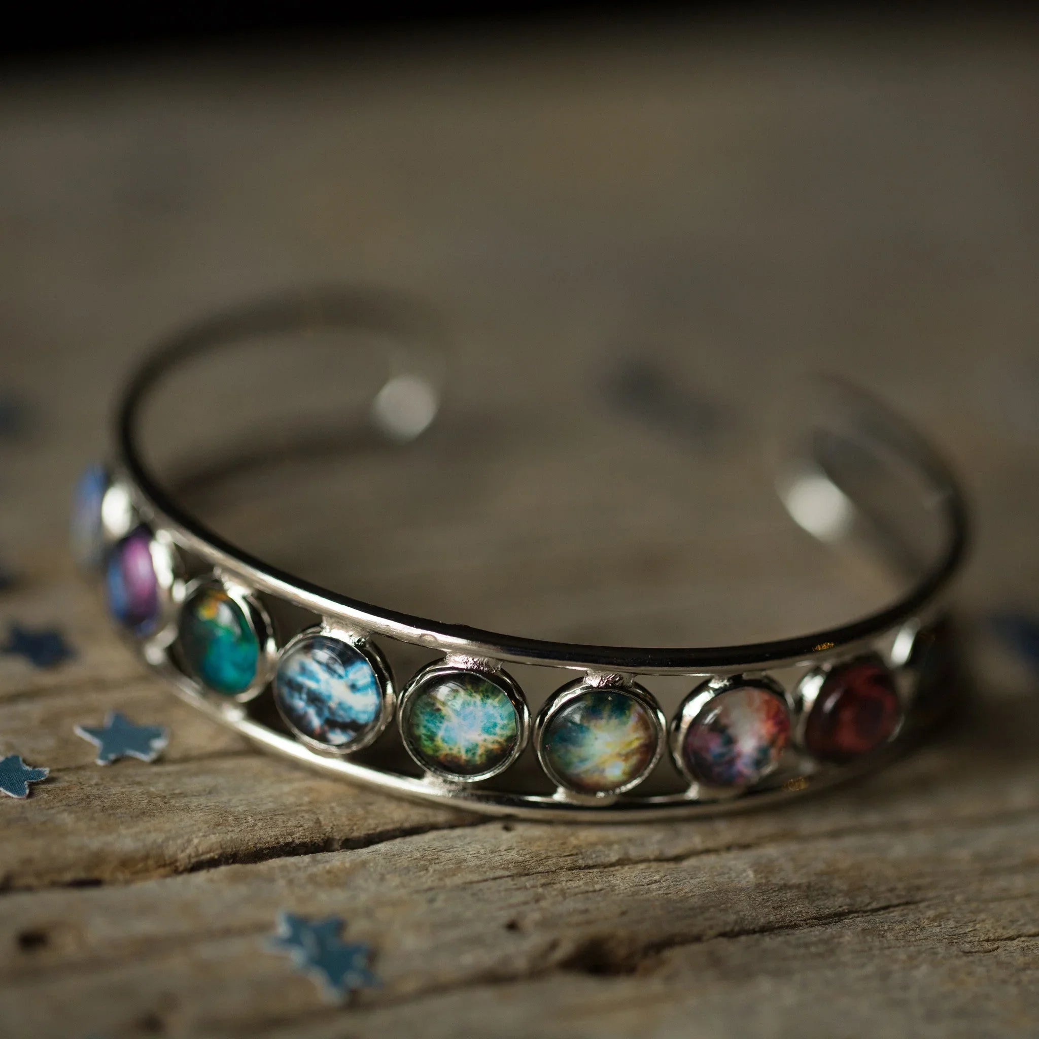 Colorful cosmic stone cuff bracelet on rustic wood, Qu!rk Boutique artist-designed jewelry