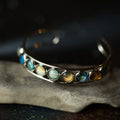 Silver cuff bracelet featuring miniature planetary gems on a dark textured surface