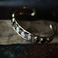 Silver cosmic-inspired cuff bracelet with round stone accents on rock, Qu!rk Boutique