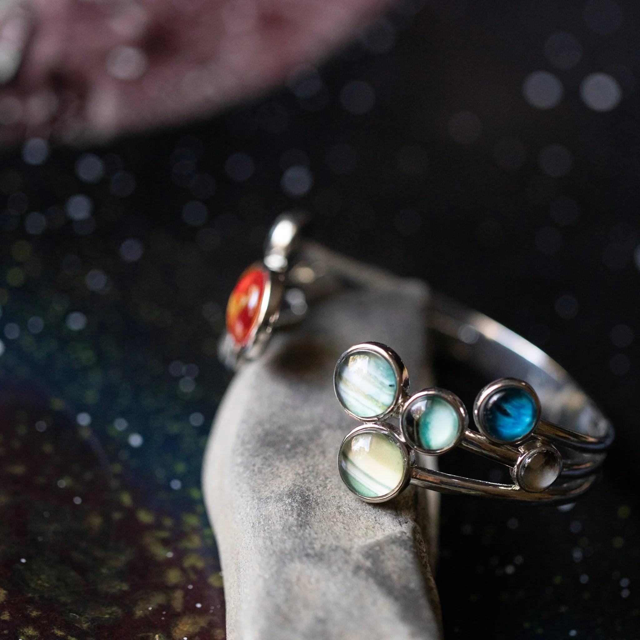 Silver planetary ring with colorful round stones placed on textured surface