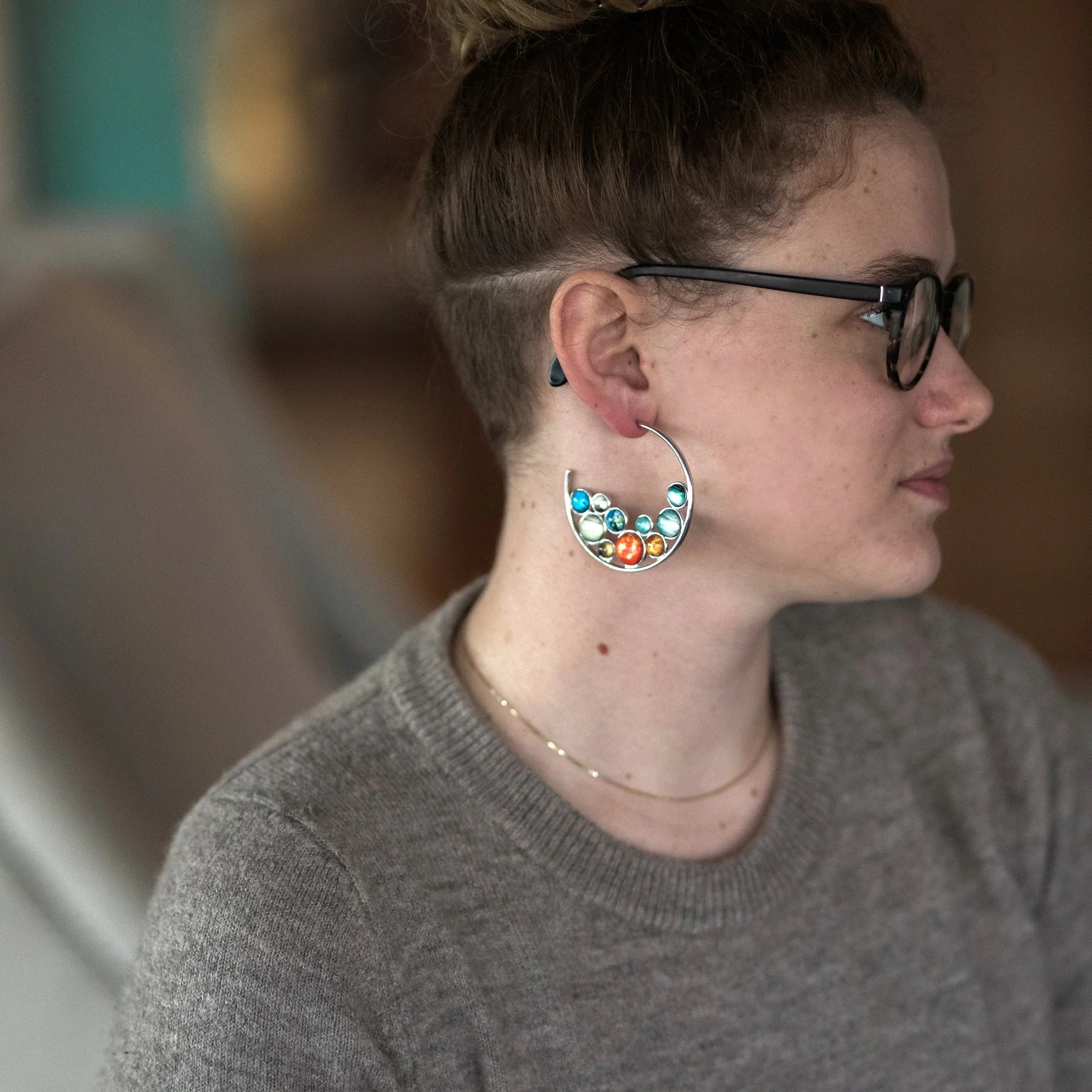 Woman wearing cosmic-inspired statement earring with colorful gems at Qu!rk Boutique
