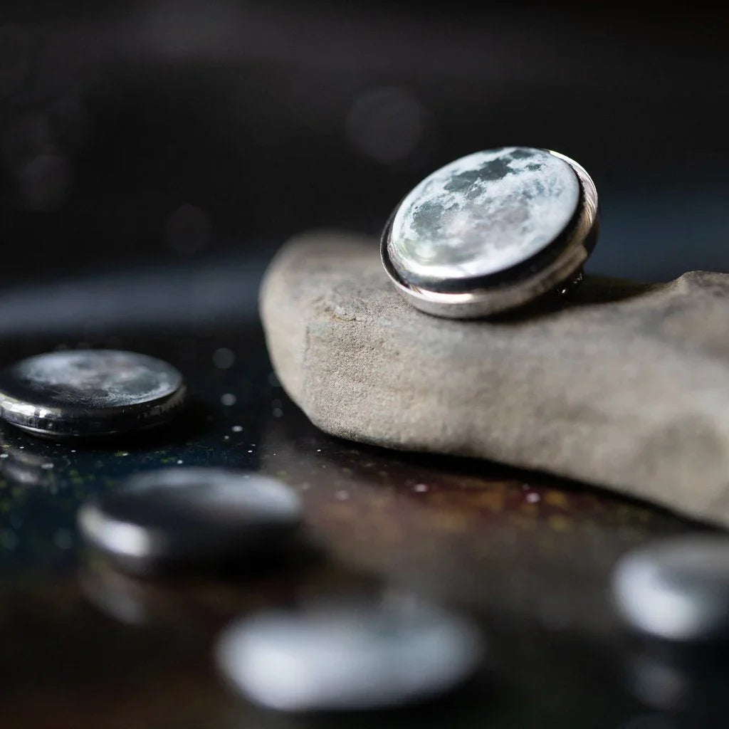 Close-up of moon-themed round pins on a stone with a dark, blurred background