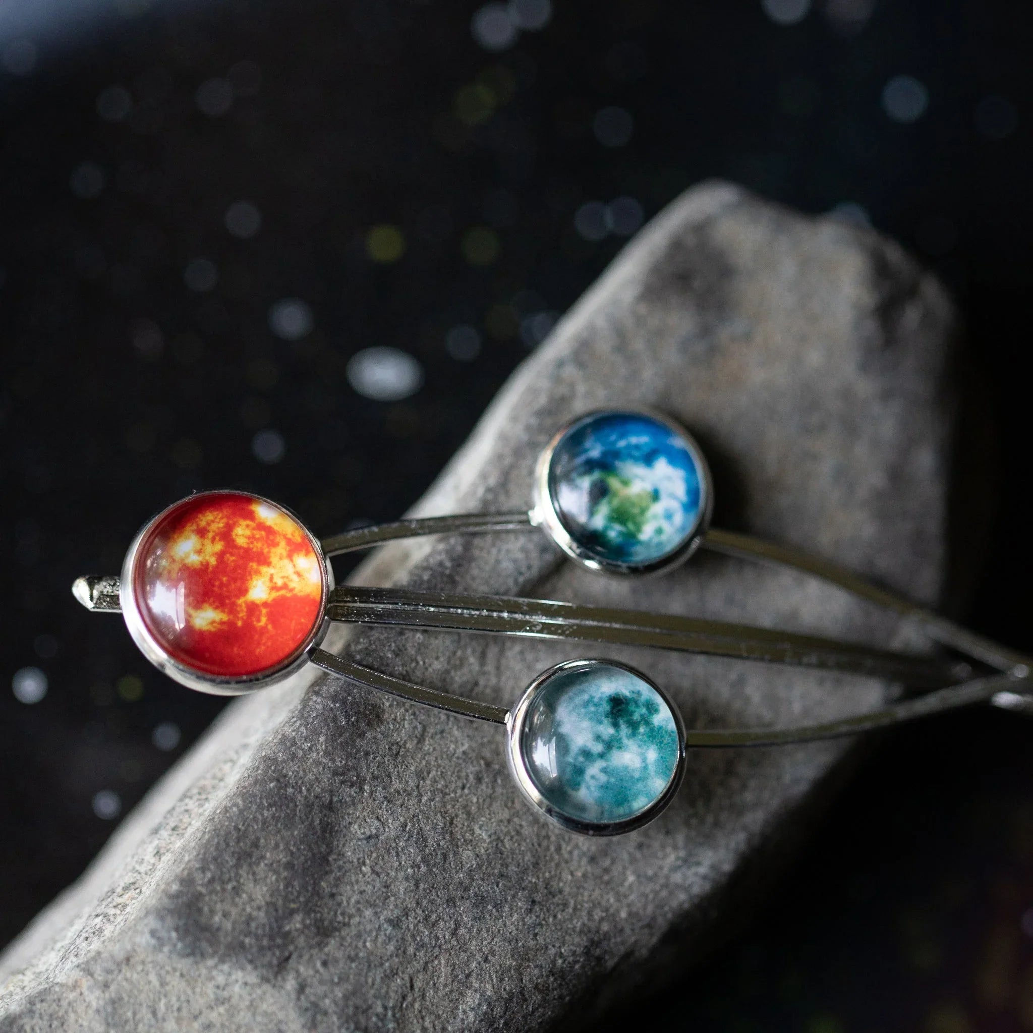 Solar system-themed hairpins with sun, earth, and moon designs on textured stone