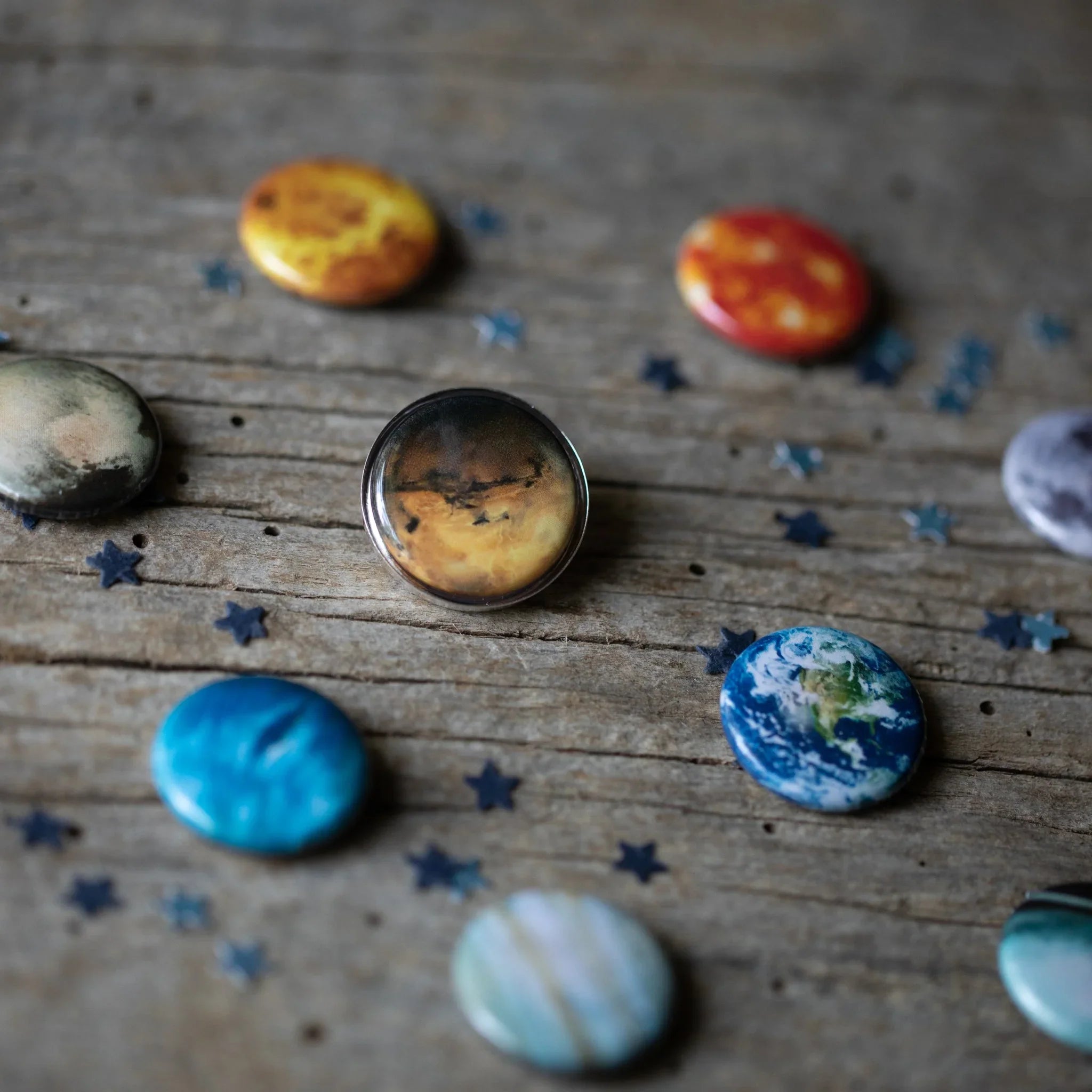 Round planet-themed buttons and star-shaped confetti on rustic wooden surface