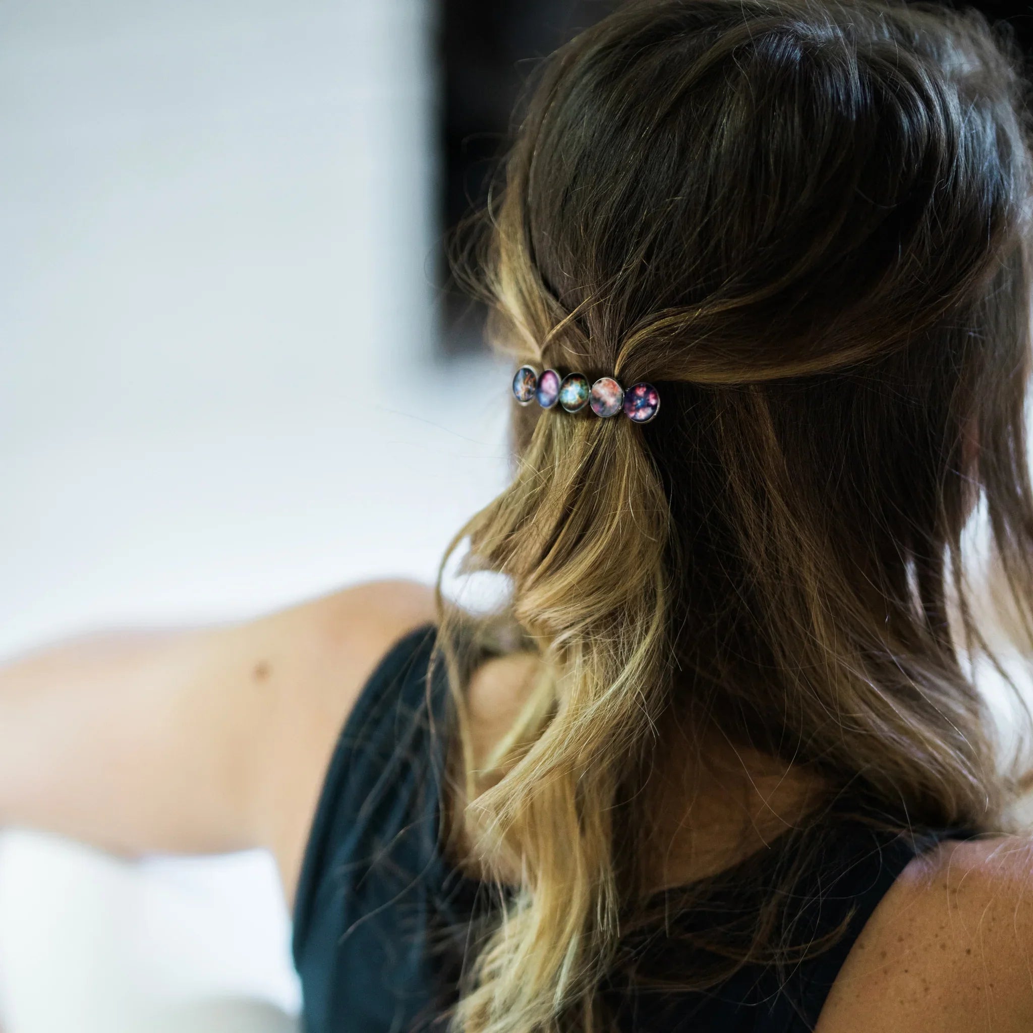 Woman with blonde hair wearing a galaxy-themed hair barrette holding back half her hair