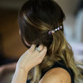 Woman with blonde hair wearing a galaxy-themed hair clip and wedding rings on her hand