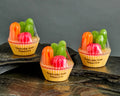 Three colorful goat's milk soaps shaped like cacti in yellow cups labeled Desert Eve on black stone slabs