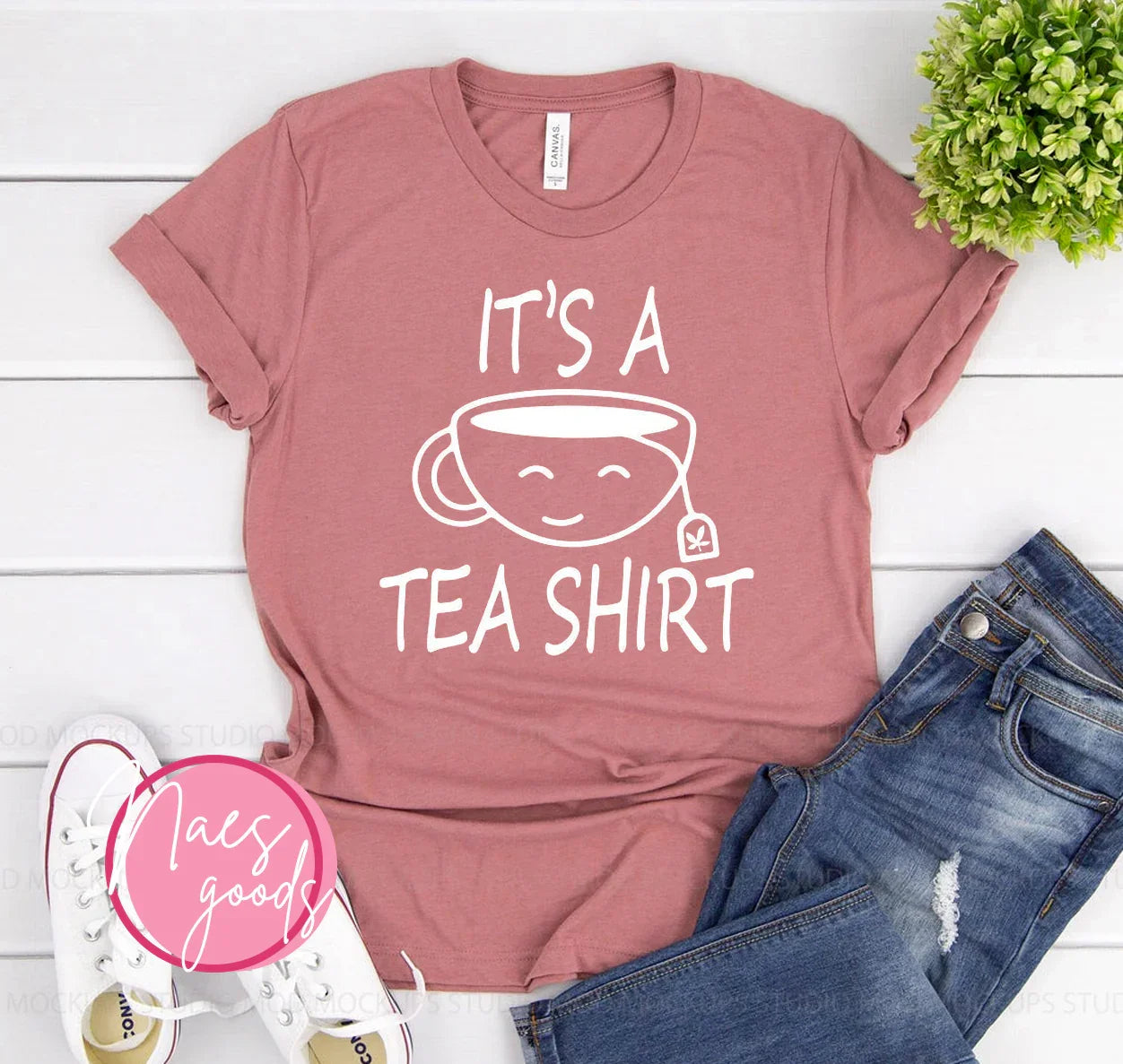 Pink t-shirt with white text and smiling tea cup graphic saying It's a tea shirt, styled with jeans and white sneakers