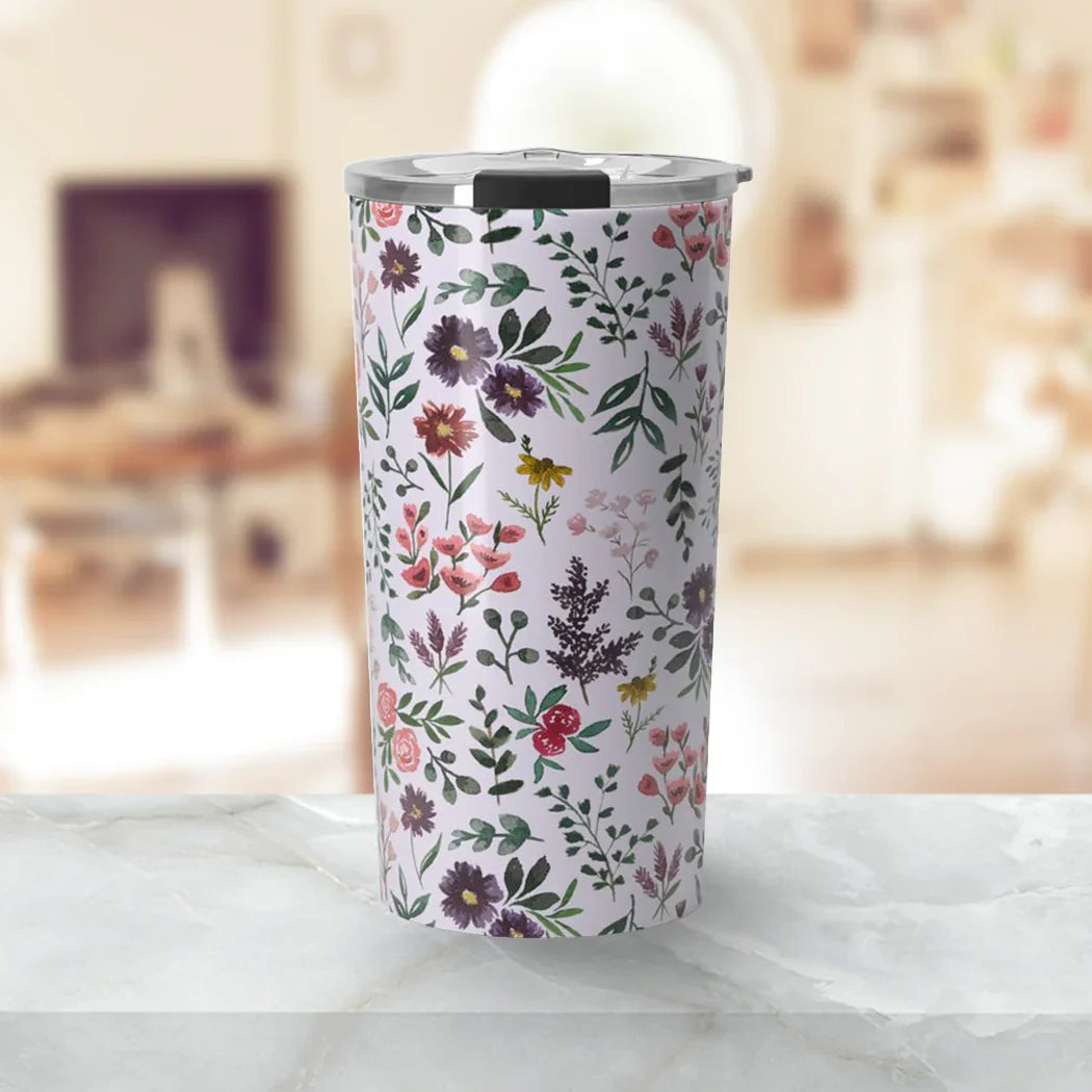 Floral patterned insulated tumbler with metal lid on marble countertop in bright room