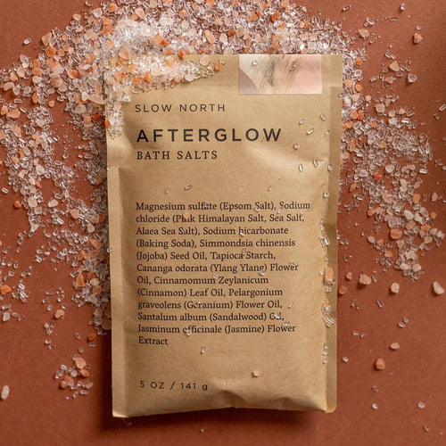 Afterglow bath salts pouch by Slow North on brown surface with pink Himalayan salt crystals