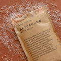 Slow North Afterglow bath salts pouch with scattered crystal salts on a warm-toned background