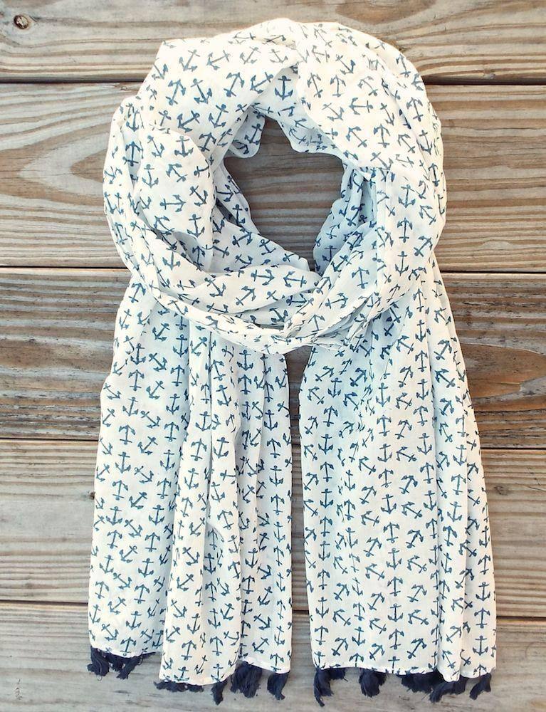 White scarf with navy blue anchor print and tassel ends, displayed on wood background