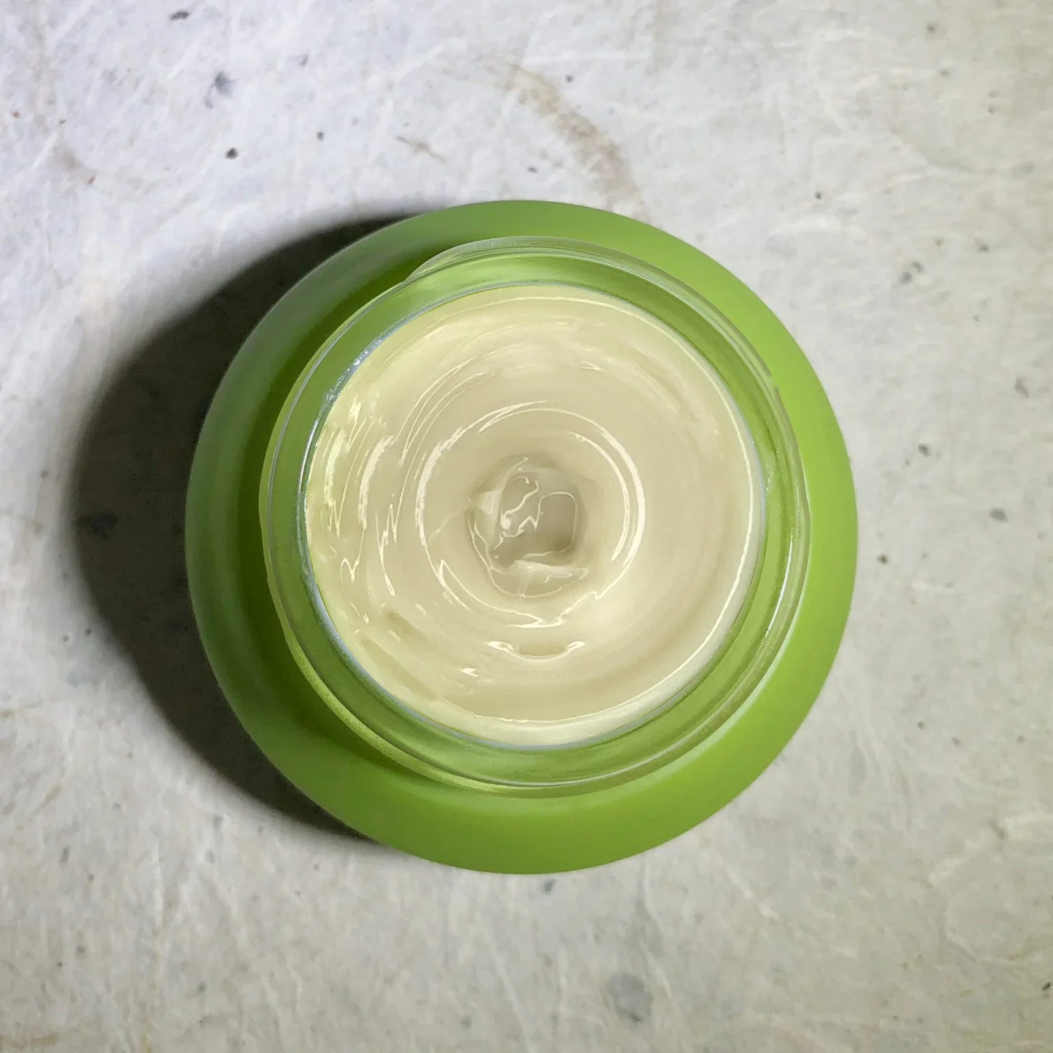 Green jar of creamy moisturizer on a textured surface, Qu!rk Boutique gift shop skincare