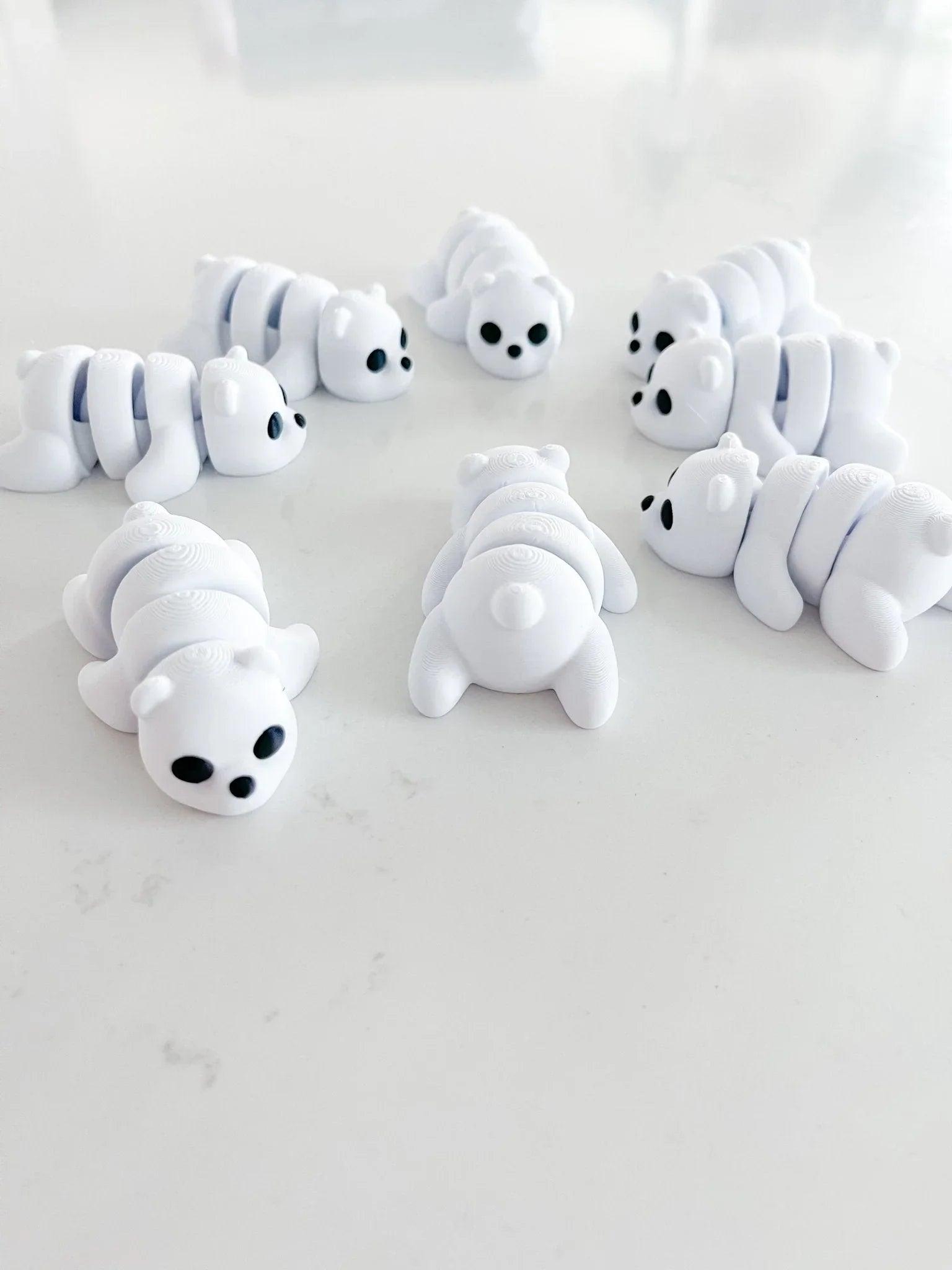 Cute white baby bear fidget toys arranged on a white surface, boutique gift shop product.