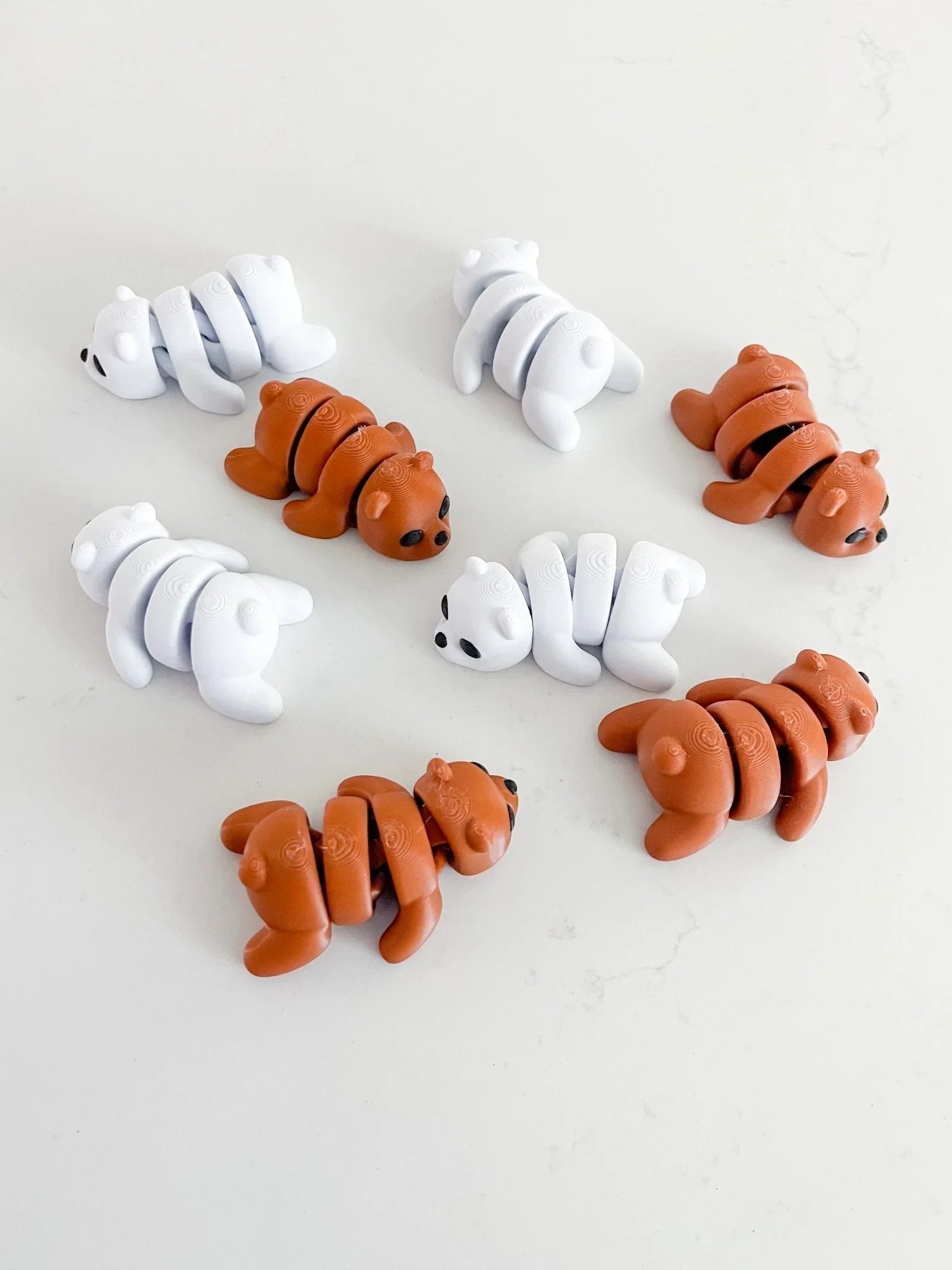 Artistic segmented bear fidget toys in white and brown on a plain surface at Qu!rk Boutique