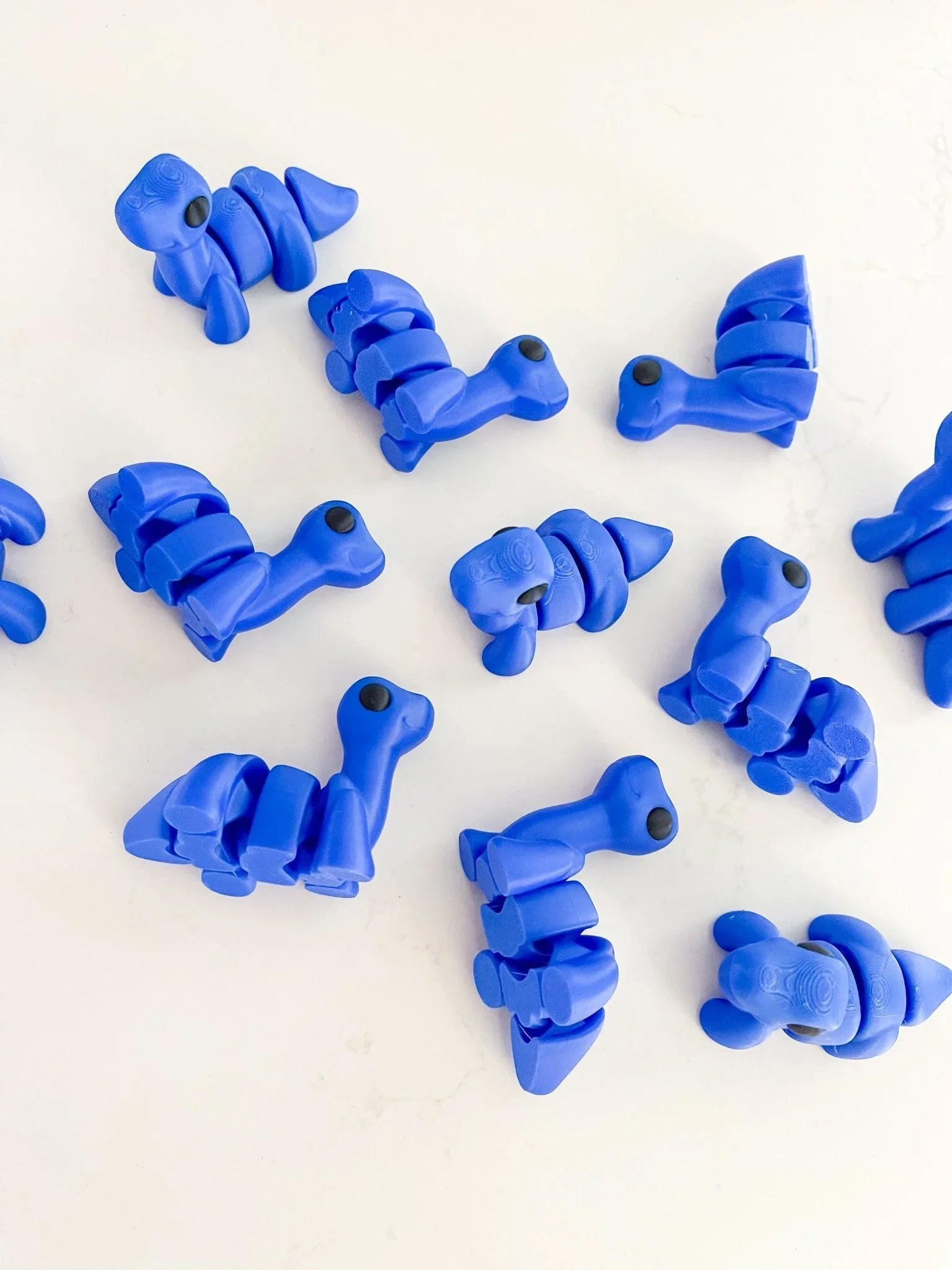 Royal blue baby dinosaur fidget toys on a white background, Qu!rk Boutique cosmic gift